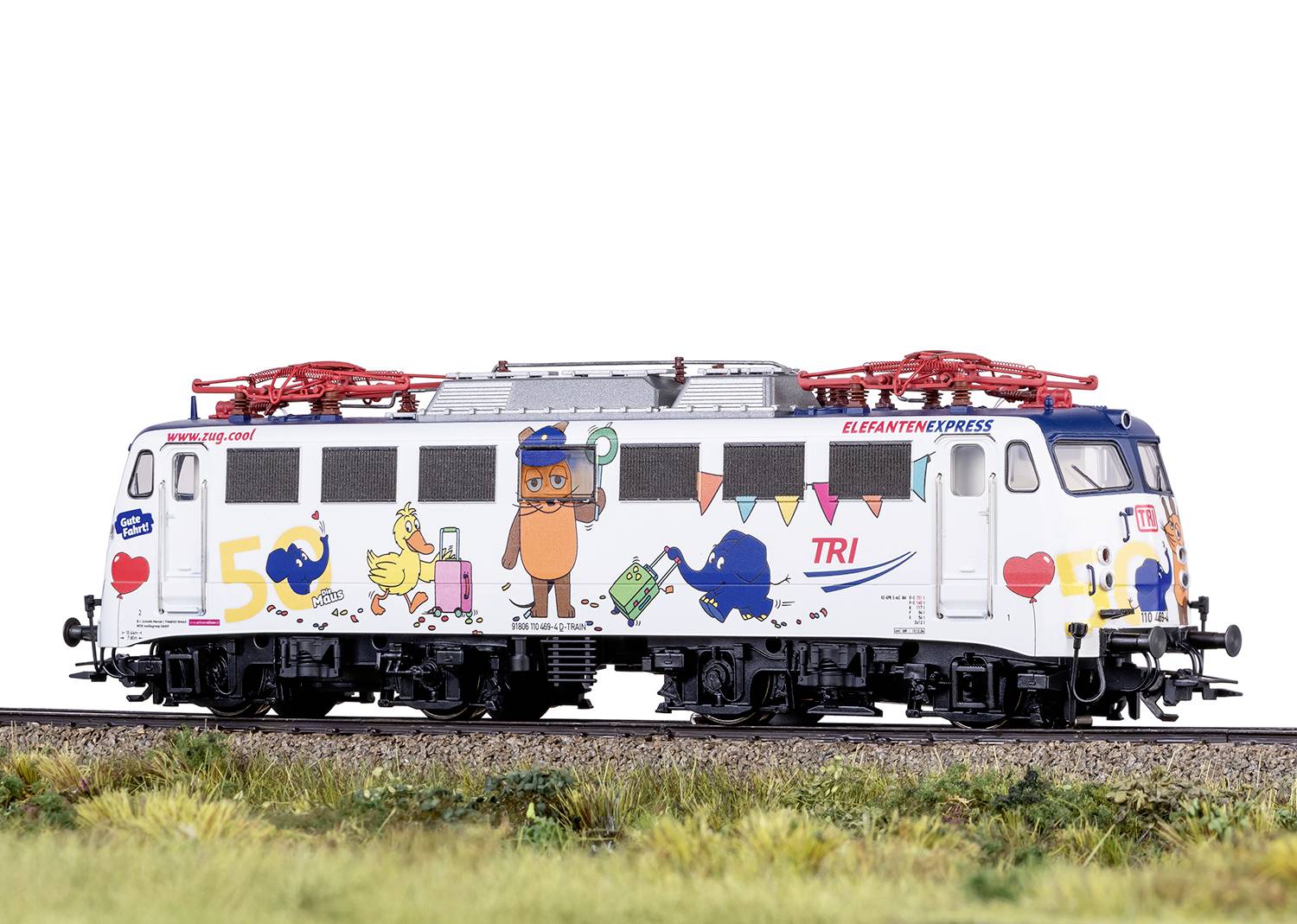 Miniaturowa lokomotywa kolejowa z kolorowymi naklejkami w stylu kreskówkowym, w tym naklejkami przedstawiającymi zwierzęta i napisy, na odcinku torów.