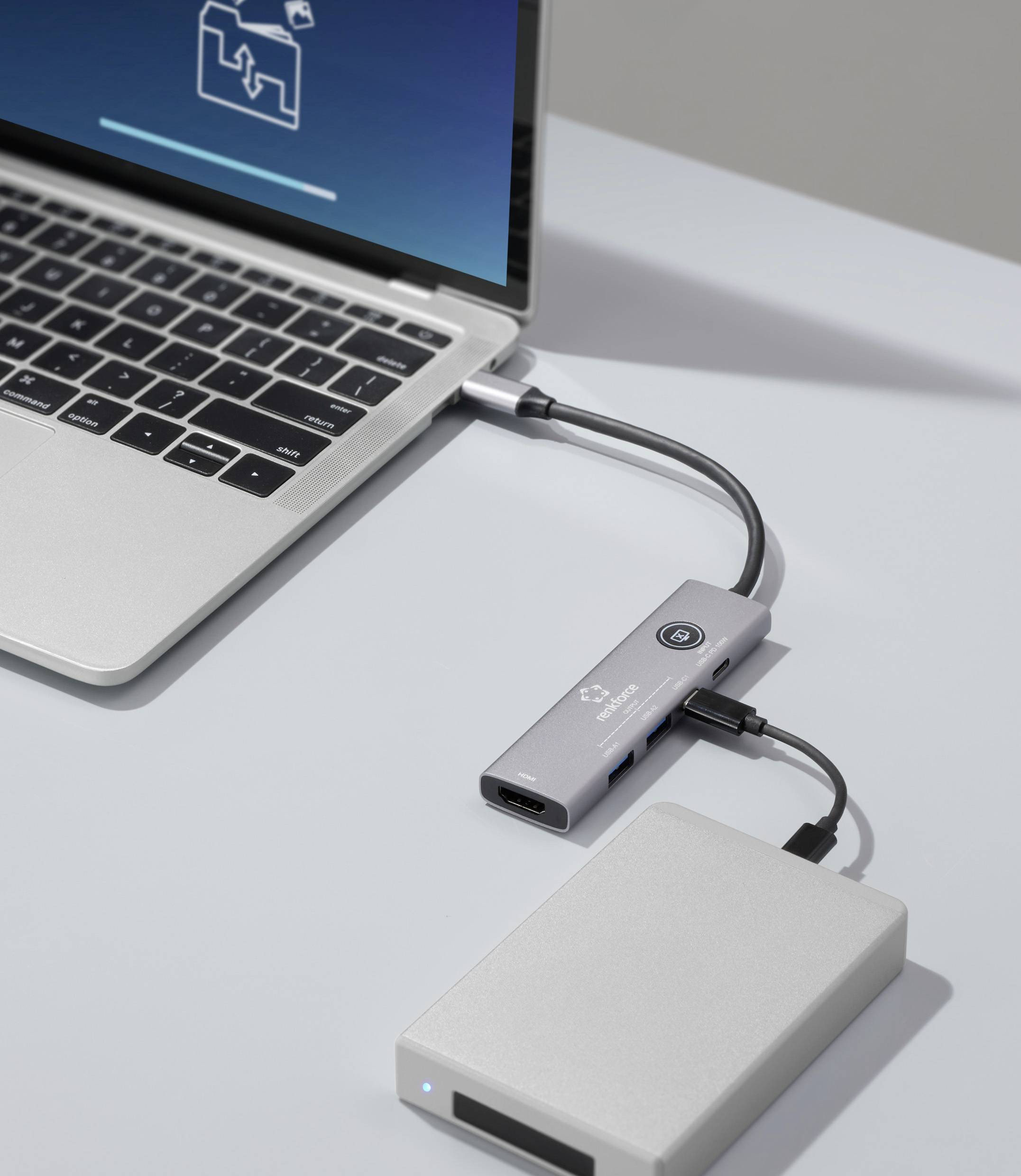 Laptop jest podłączony do zewnętrznego urządzenia poprzez koncentrator USB-C, wyświetlając transfer danych na ekranie.