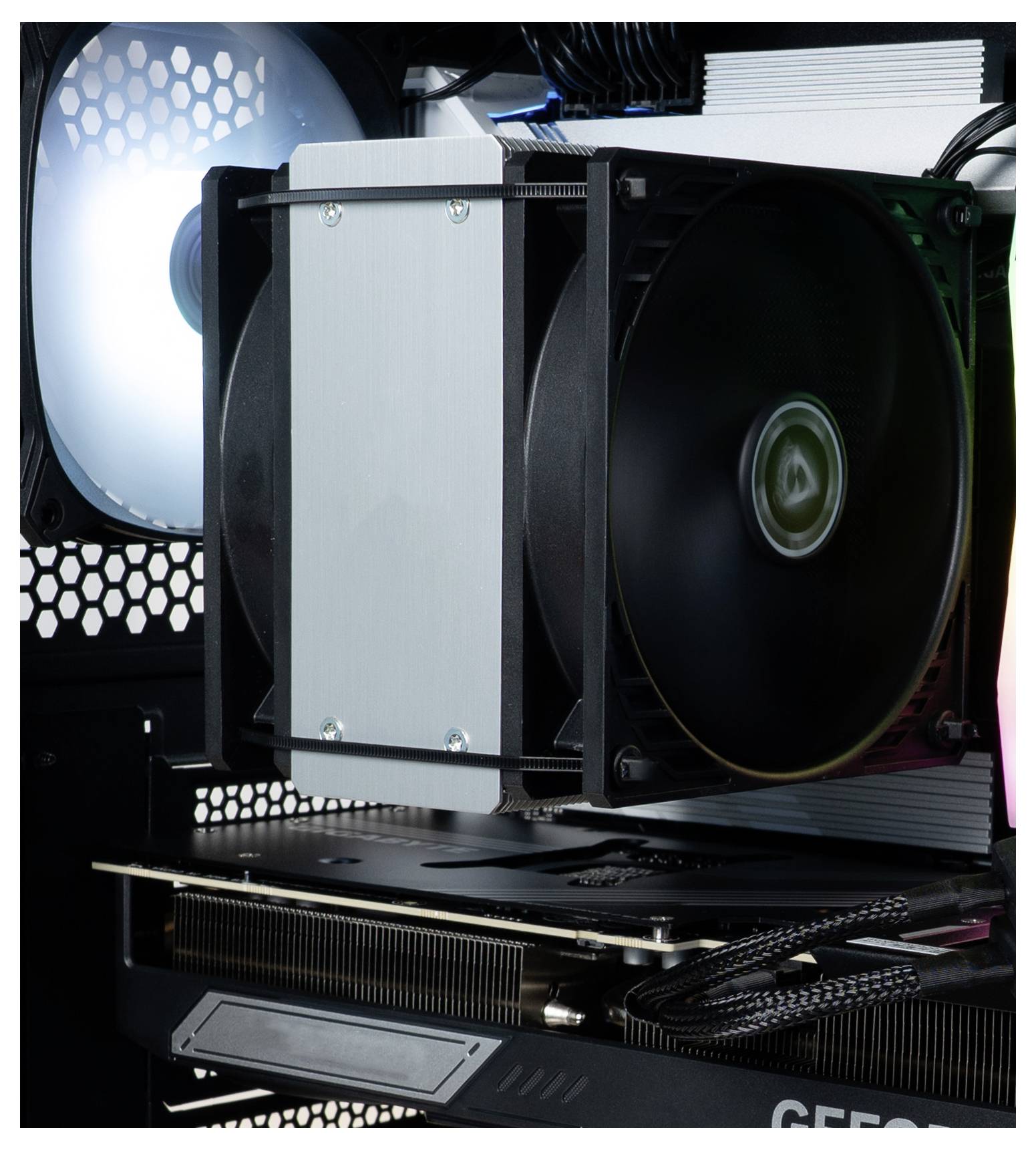 Wnętrze obudowy komputera z dużym czarnym wentylatorem chłodzącym zamocowanym do radiatora oraz częścią karty graficznej z widocznymi obwodami elektronicznymi.