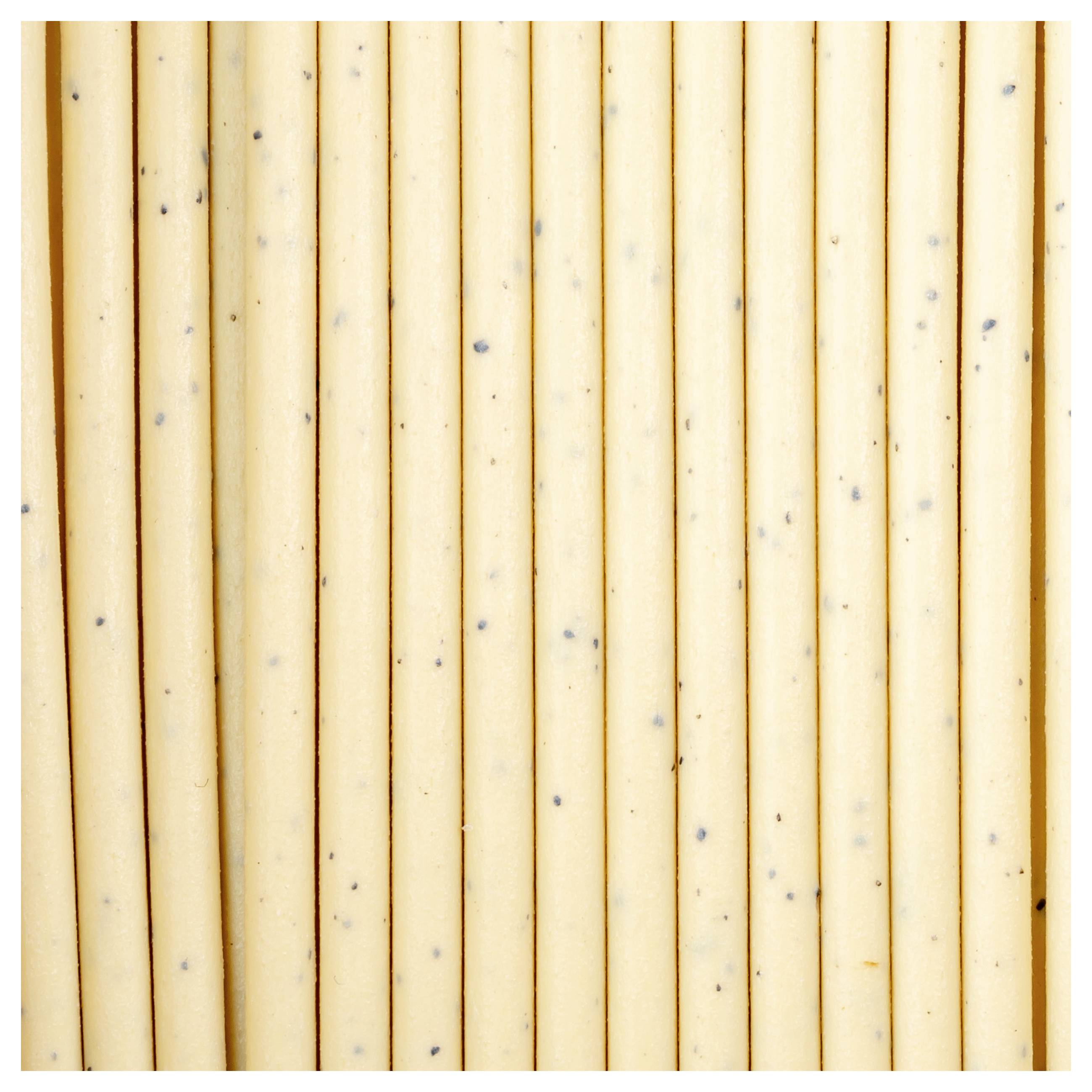 Kilka surowych spaghetti stojących pionowo na jasnym tle, ułożonych blisko siebie i z czarnymi kropkami.