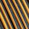 Zbliżenie na pomarańczowe i czarne paski biegnące równolegle, które mają teksturę z kurzem lub okruchami.