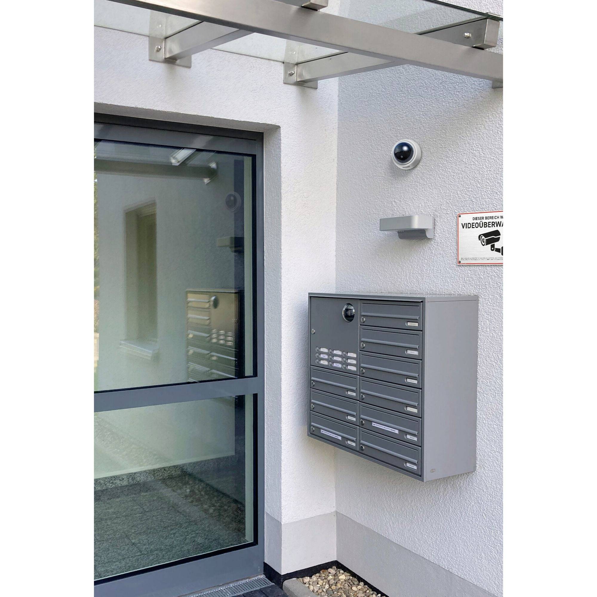 Skrzynki pocztowe i kamery monitoringu przy wejściu do budynku