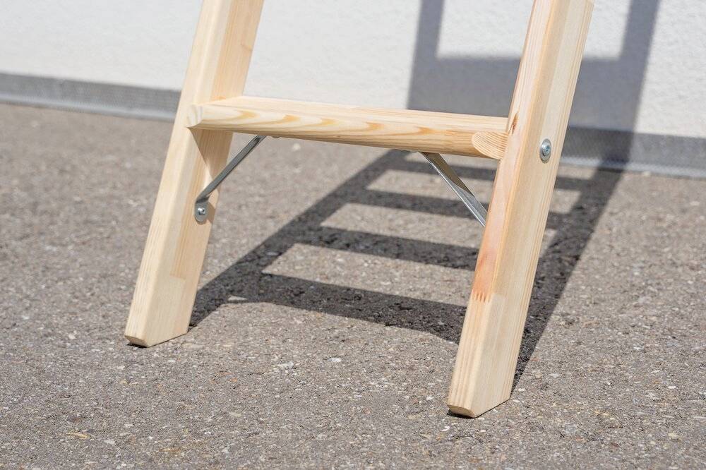 Drewniany stopień schodów rzucający cień na betonową podłogę w świetle dziennym.