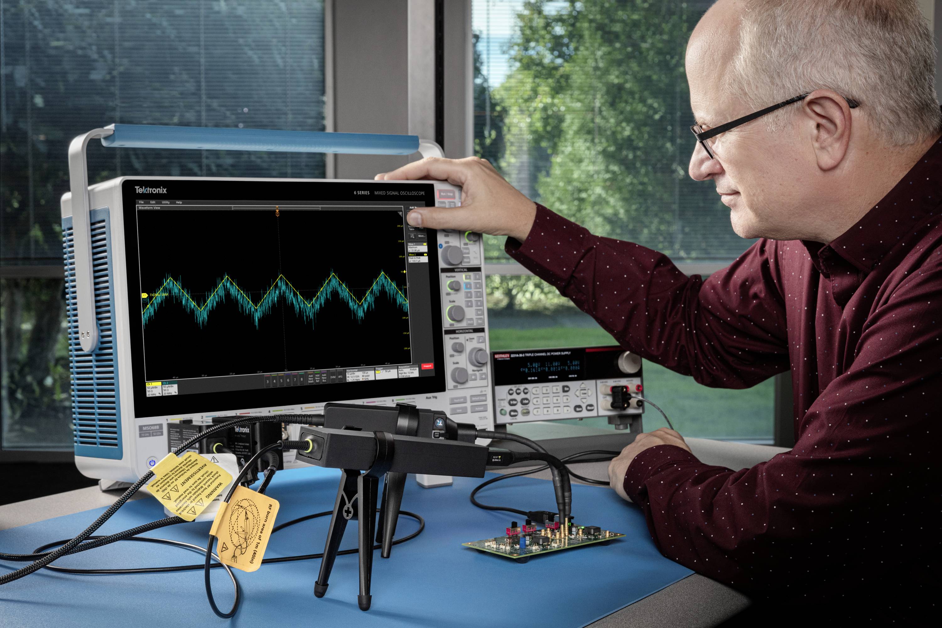 Mężczyzna obsługuje oscyloskop, aby analizować przebiegi fal na ekranie. Układ scalony jest podłączony do urządzenia.