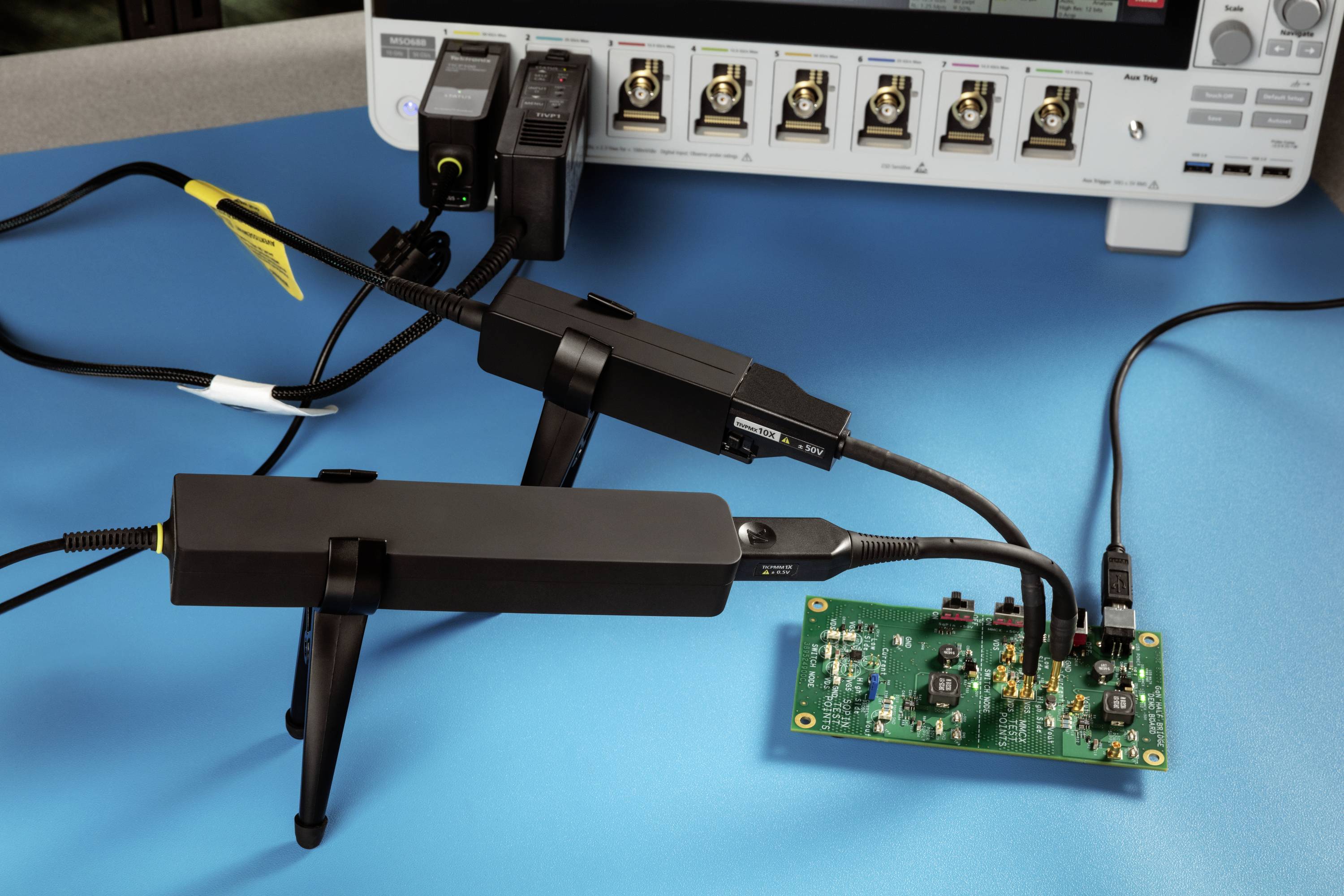 Oscyloskop z podłączonymi sondami mierzy sygnały na płytce drukowanej. Na tle widoczne są złącza.