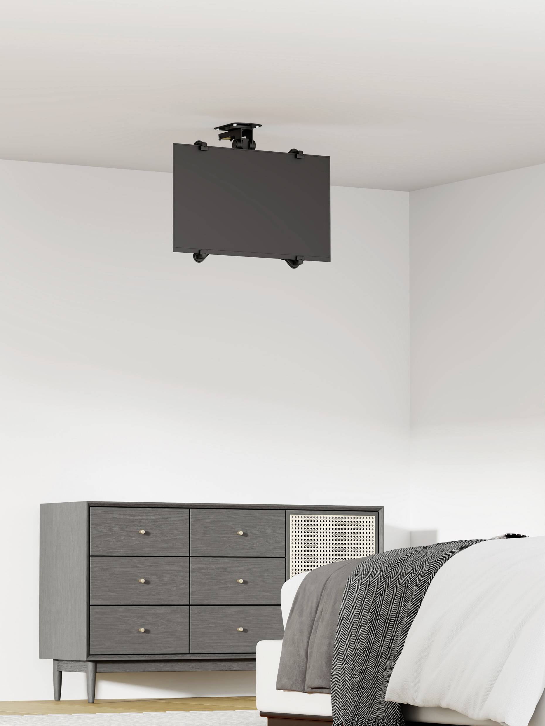 Szary pokój przedstawia komodę po lewej stronie i łóżko po prawej. Na suficie wisi płaski ekran.