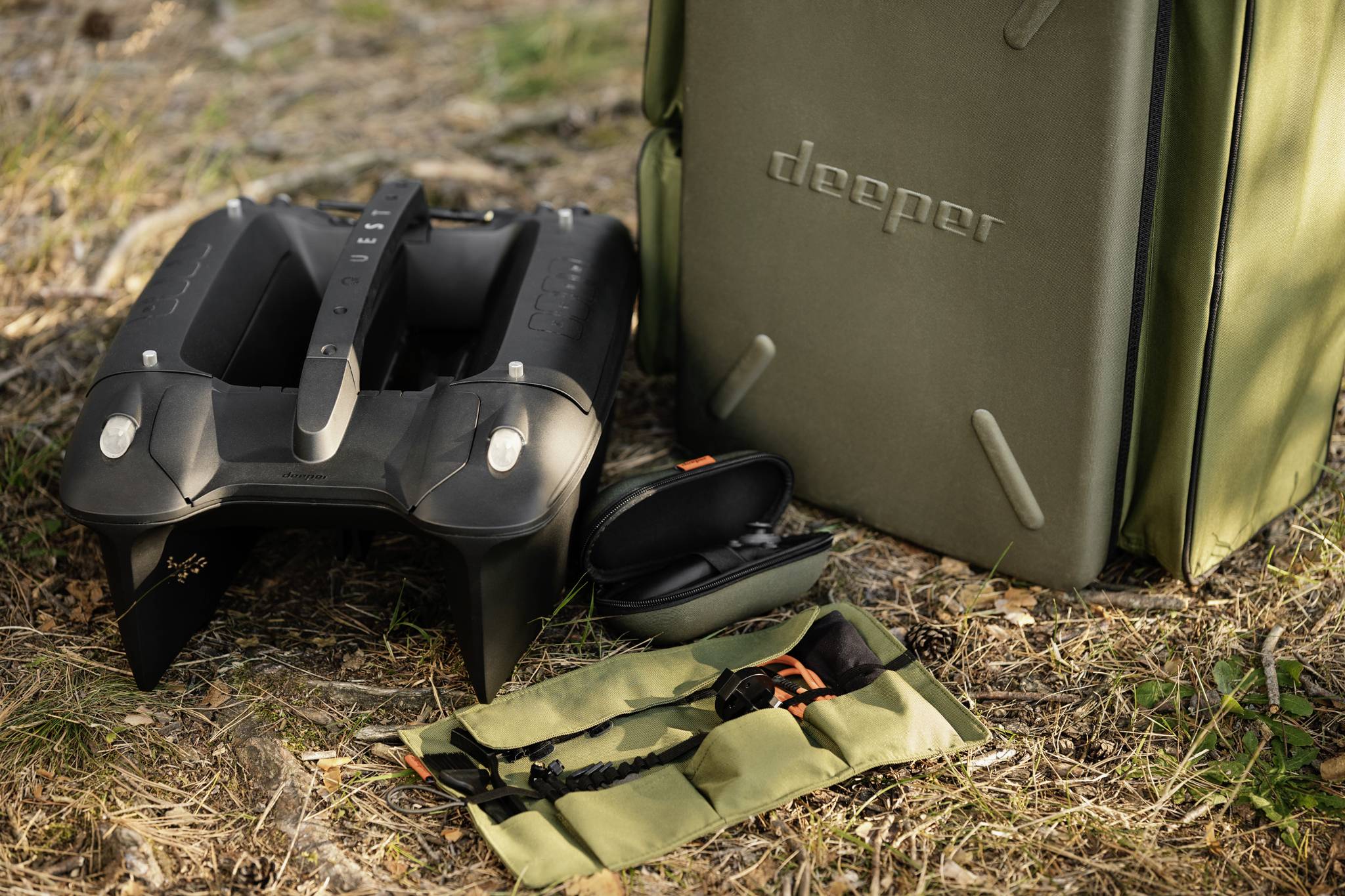 Czarny sprzęt wodny leży na podłodze obok oliwkowozielonej torby.Bok torby jest uzupełniony małą torebką z akcesoriami.