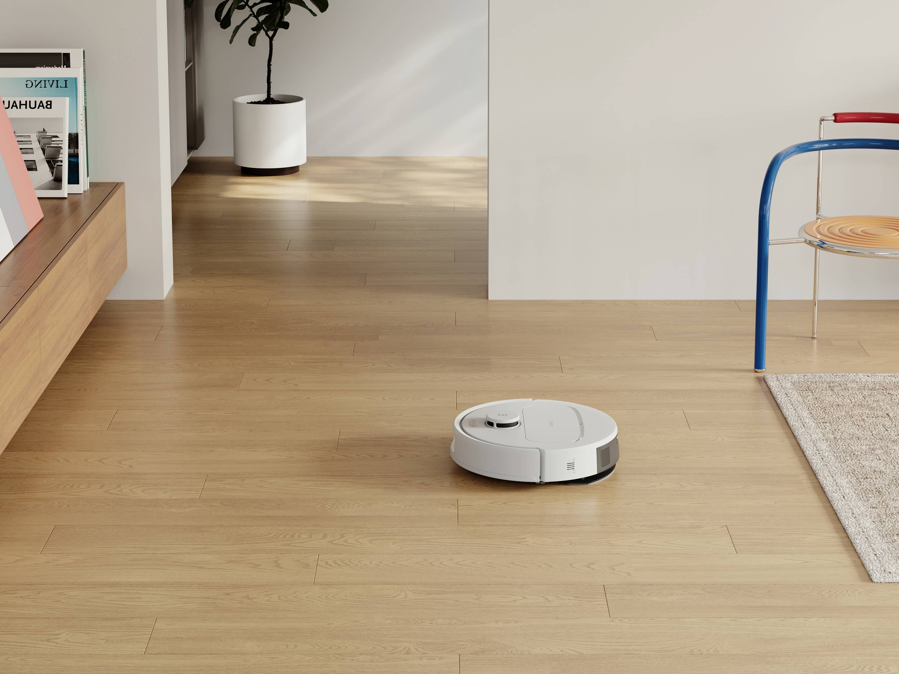 Biały robot sprzątający na jasnej drewnianej podłodze w salonie, obok niebieskiego krzesła i doniczki z rośliną.