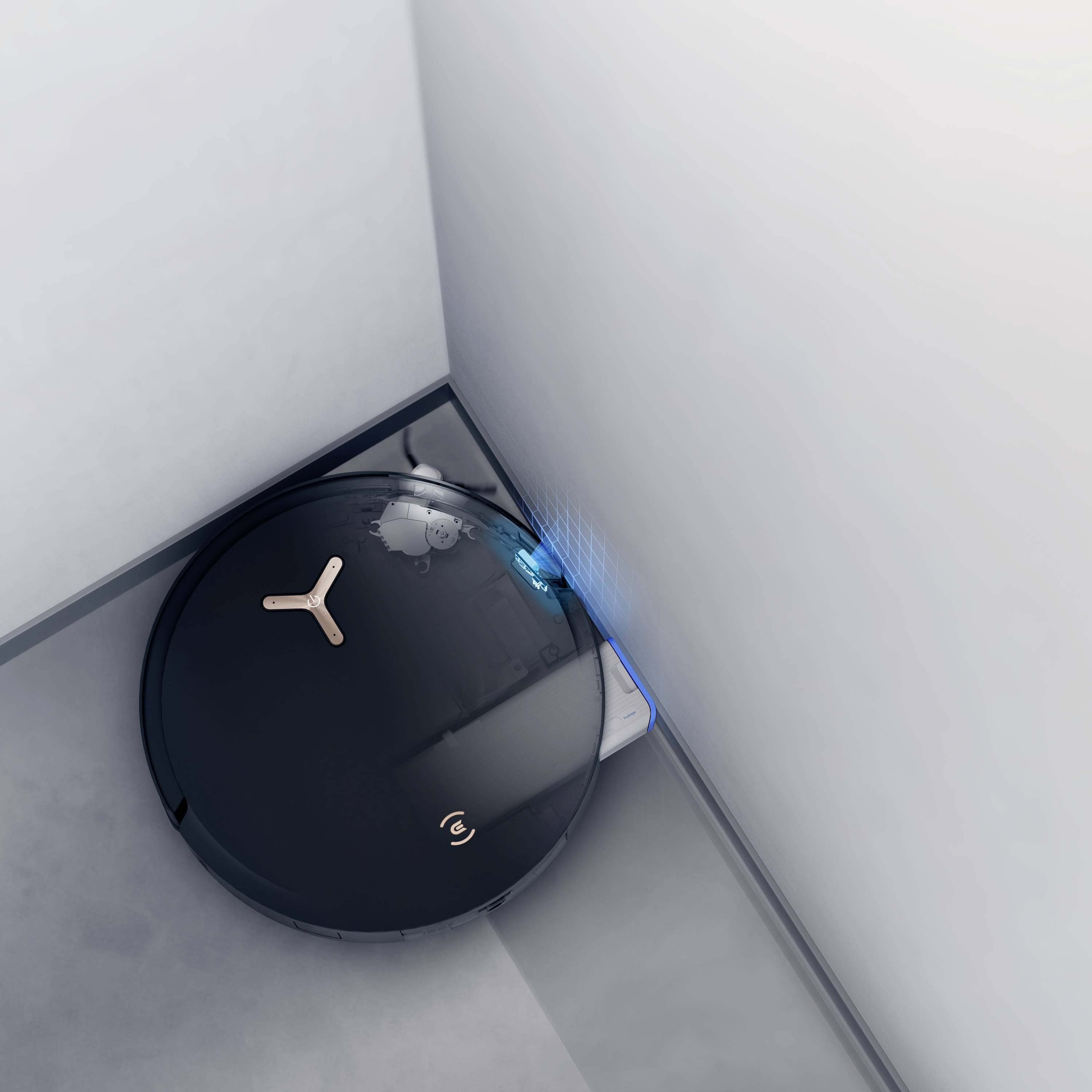 Czarny robot odkurzający czyści róg pomieszczenia. Niebieskie światła wskazują, że robot jest w trakcie pracy.