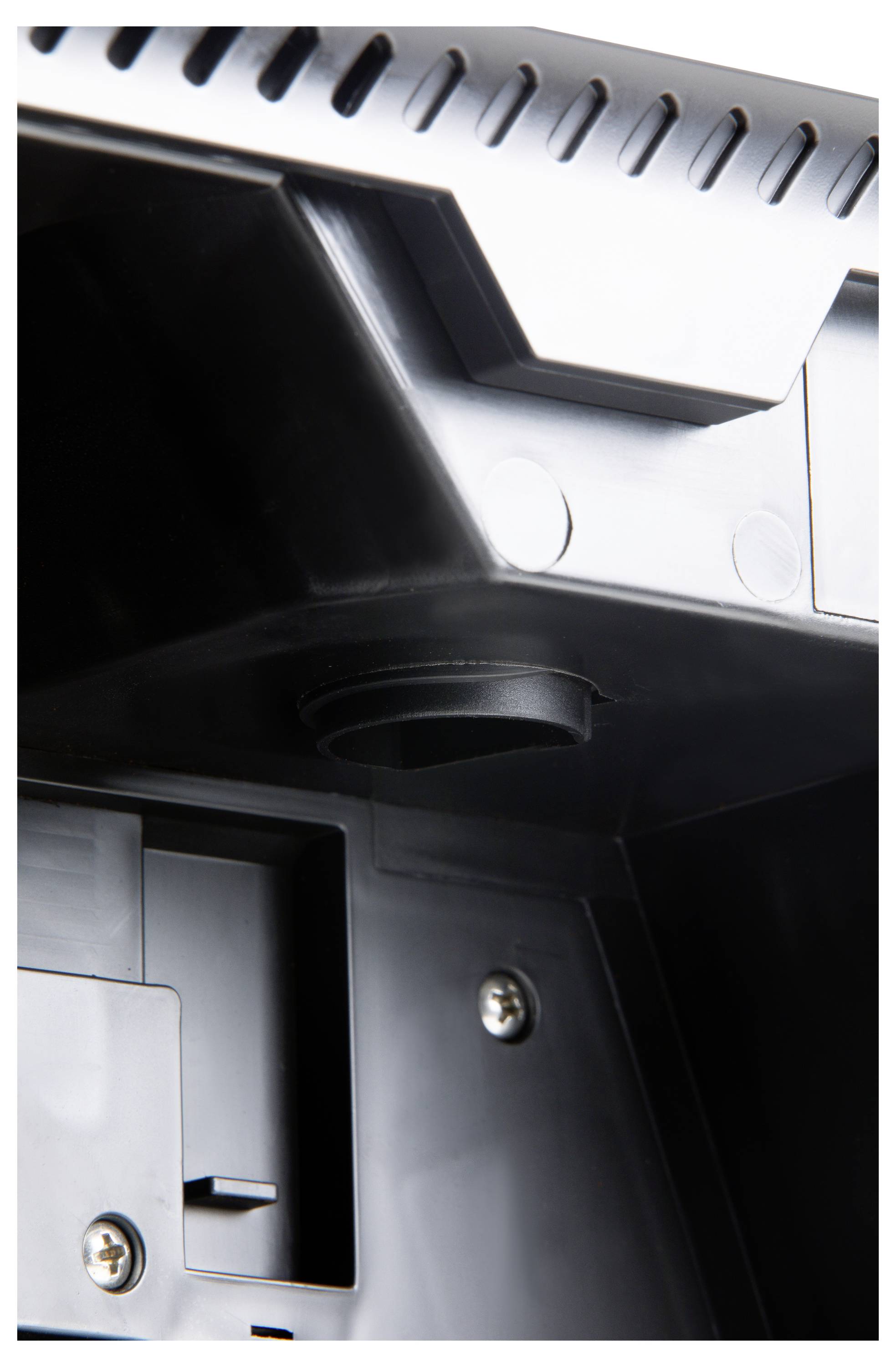 Zbliżenie fragmentu urządzenia elektronicznego, z widocznymi śrubami i okrągłym złączem, otoczone czarnym tworzywem sztucznym.