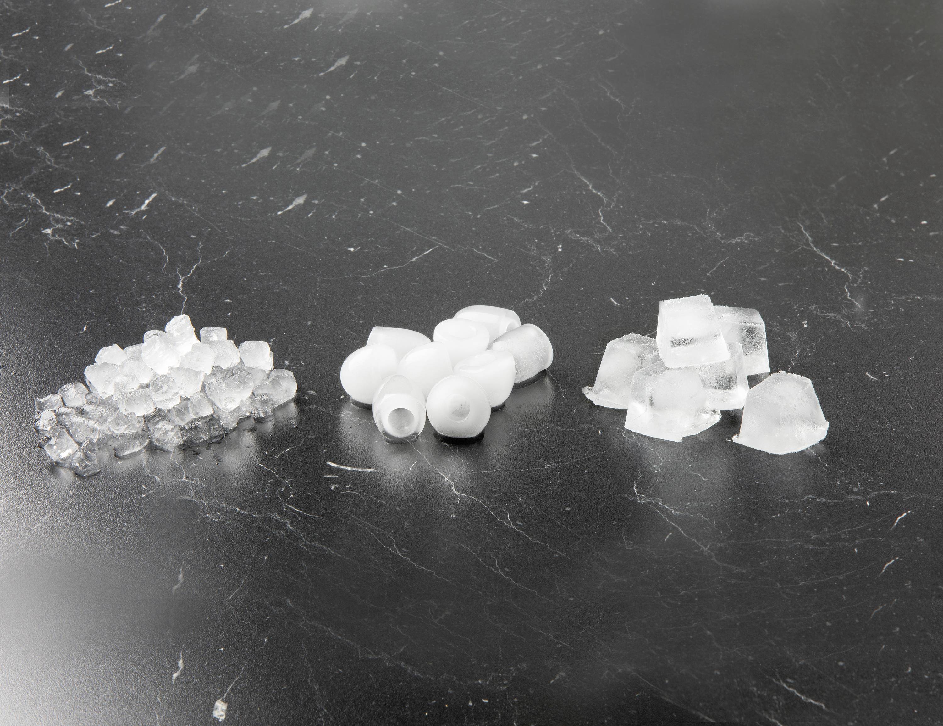 Trzy małe kupki na czarnym tle: po lewej cukier, pośrodku białe obiektywy, a po prawej kostki lodu.