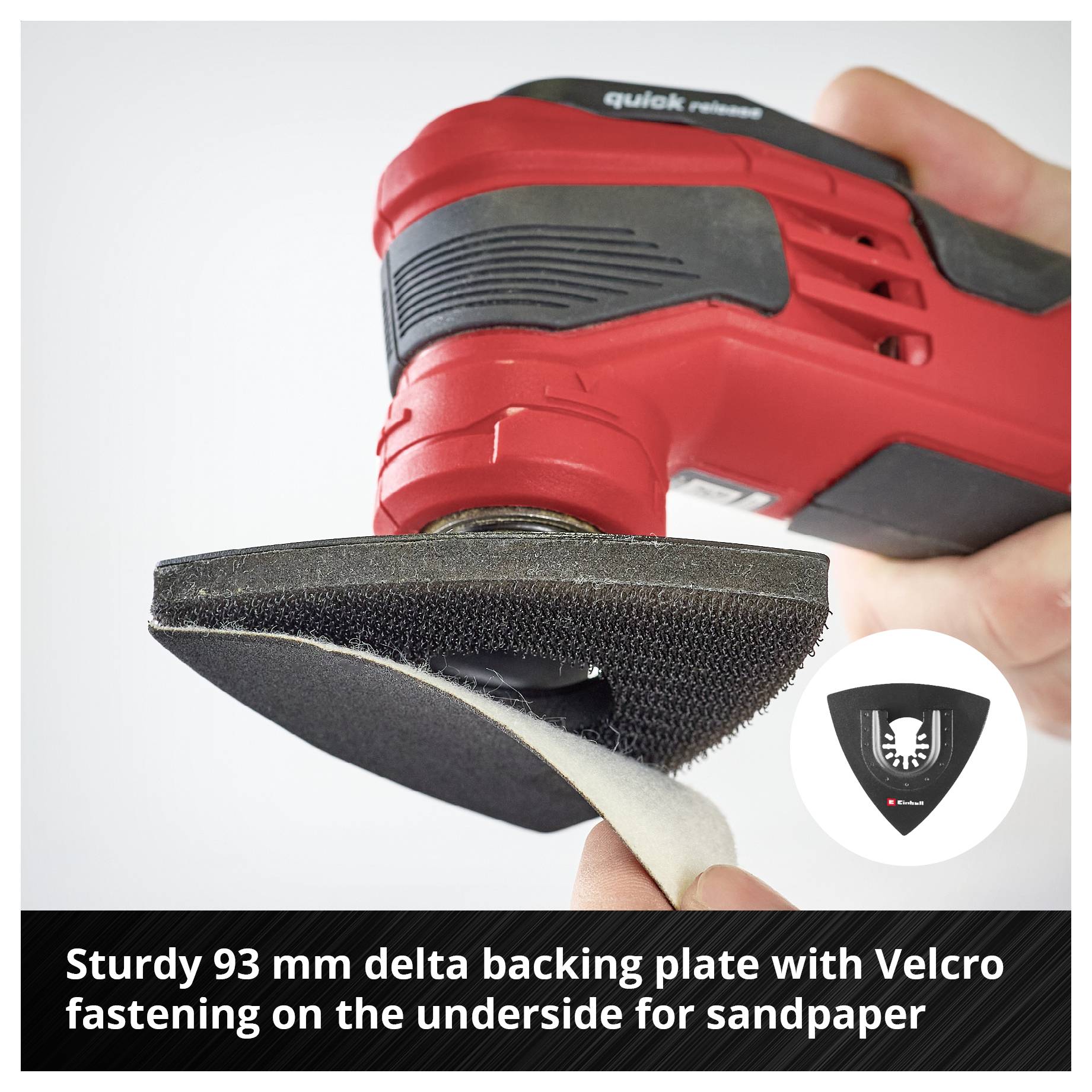 Prawa ręka trzyma czerwoną wielofunkcyjną szlifierkę z 93-mm trójkątnym talerzem nośnym, na którym zamocowany jest papier ścierny z rzepem.