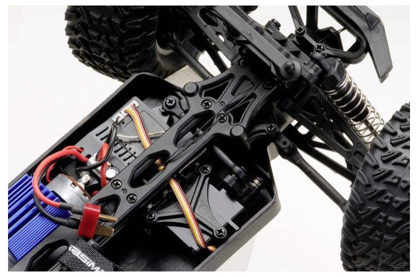 Zbliżenie na wewnętrzne mechanizmy samochodu zdalnie sterowanego, pokazujące skomplikowane okablowanie, system zawieszenia i komponenty silnika.