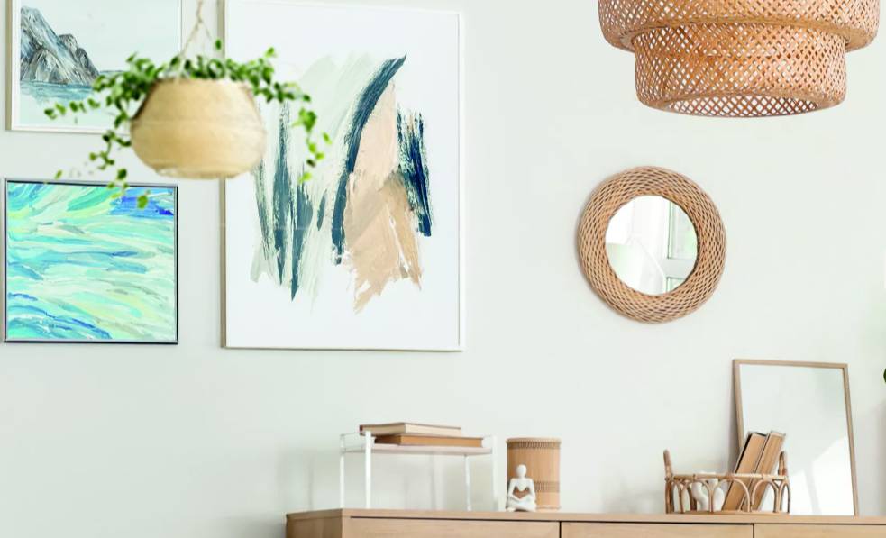 Prosty, nowoczesny salon z wiszącymi roślinami, abstrakcyjną sztuką na ścianie, lustrem i minimalistyczną drewnianą półką.