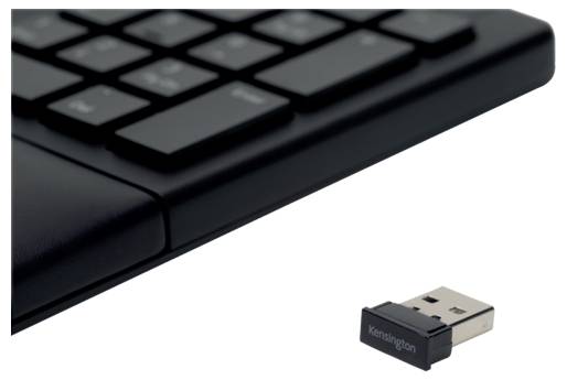 Czarna klawiatura komputerowa leży obok adaptera USB oznaczonego logo 'Kensington'.