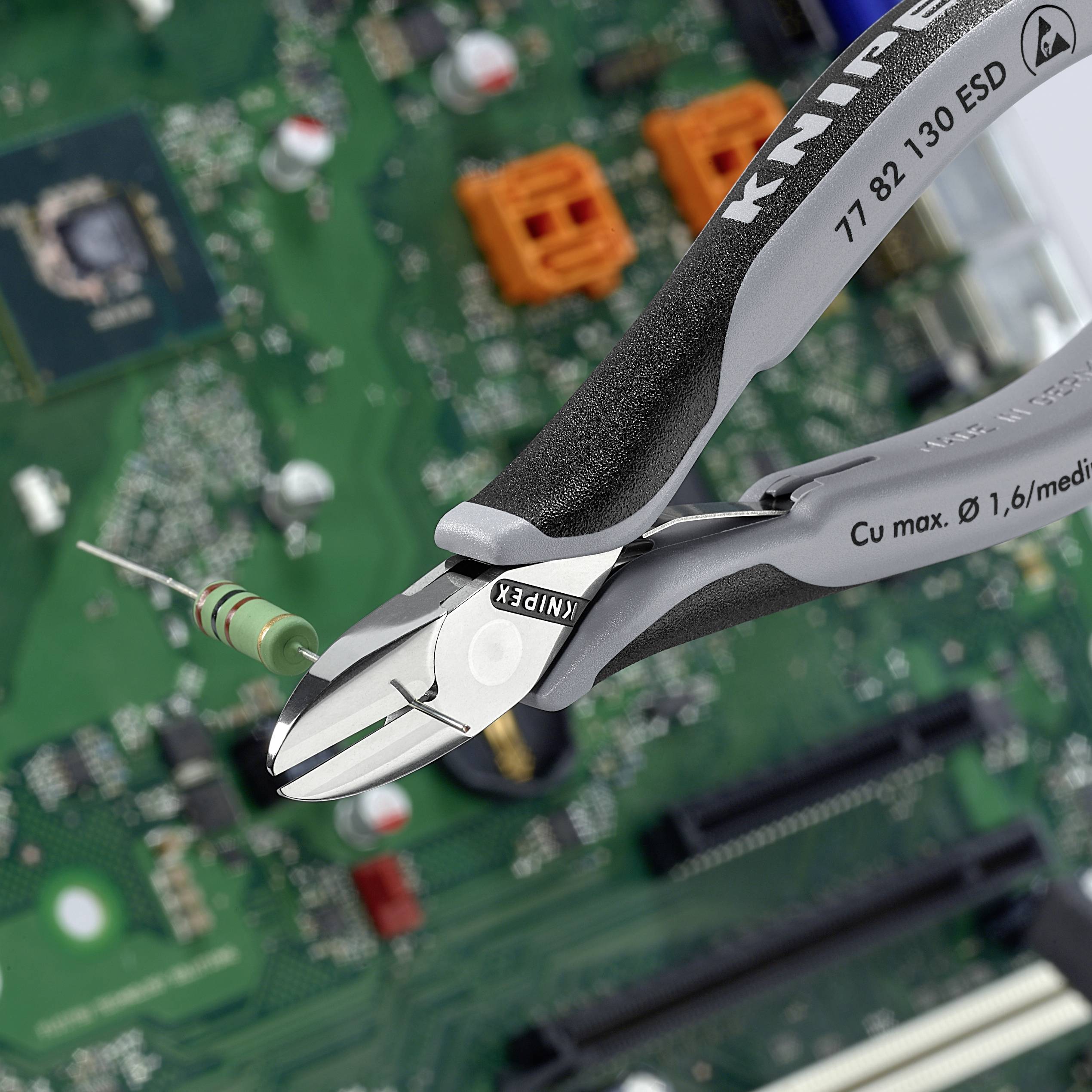 Szczypki przecinają rezystor na płytce elektronicznej.