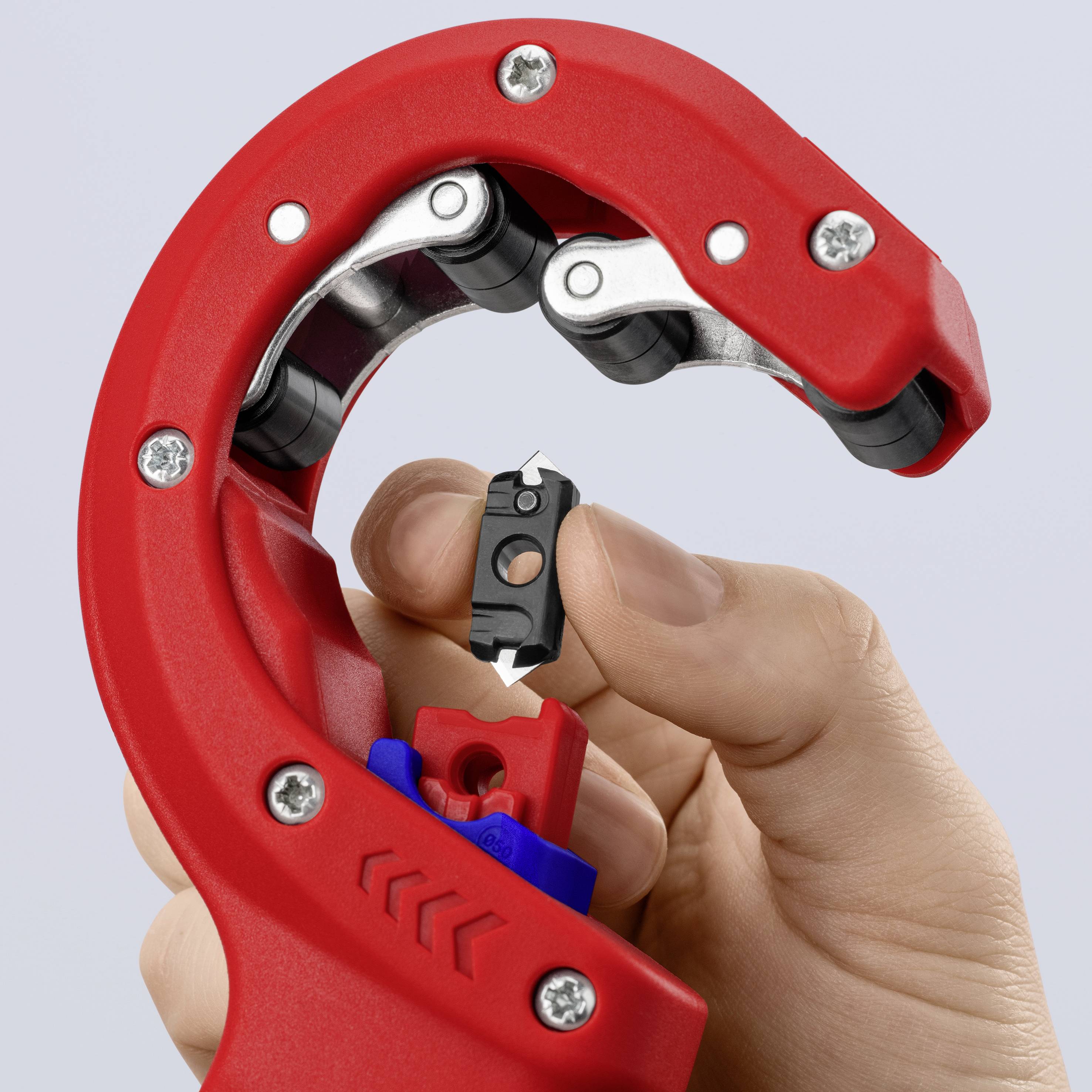 Czerwone szczypce Rohrschneider są trzymane w jednej ręce, pokazując ostrą klingę i pokrętło regulacyjne. Narzędzie jest używane do precyzyjnego cięcia rur.