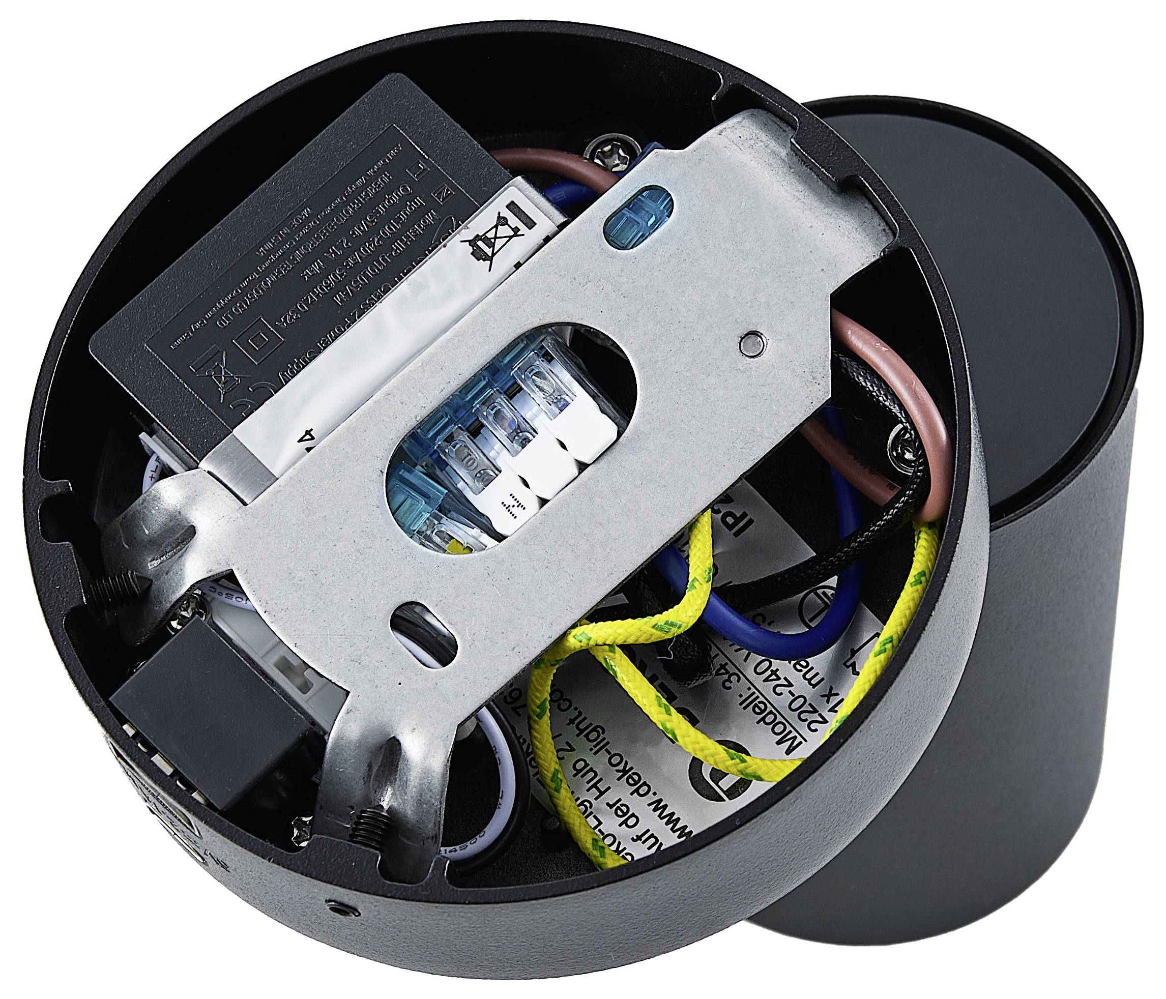 Otwarte okrągłe urządzenie elektryczne z widocznymi przewodami i elementami, w tym baterią, w czarnej obudowie.