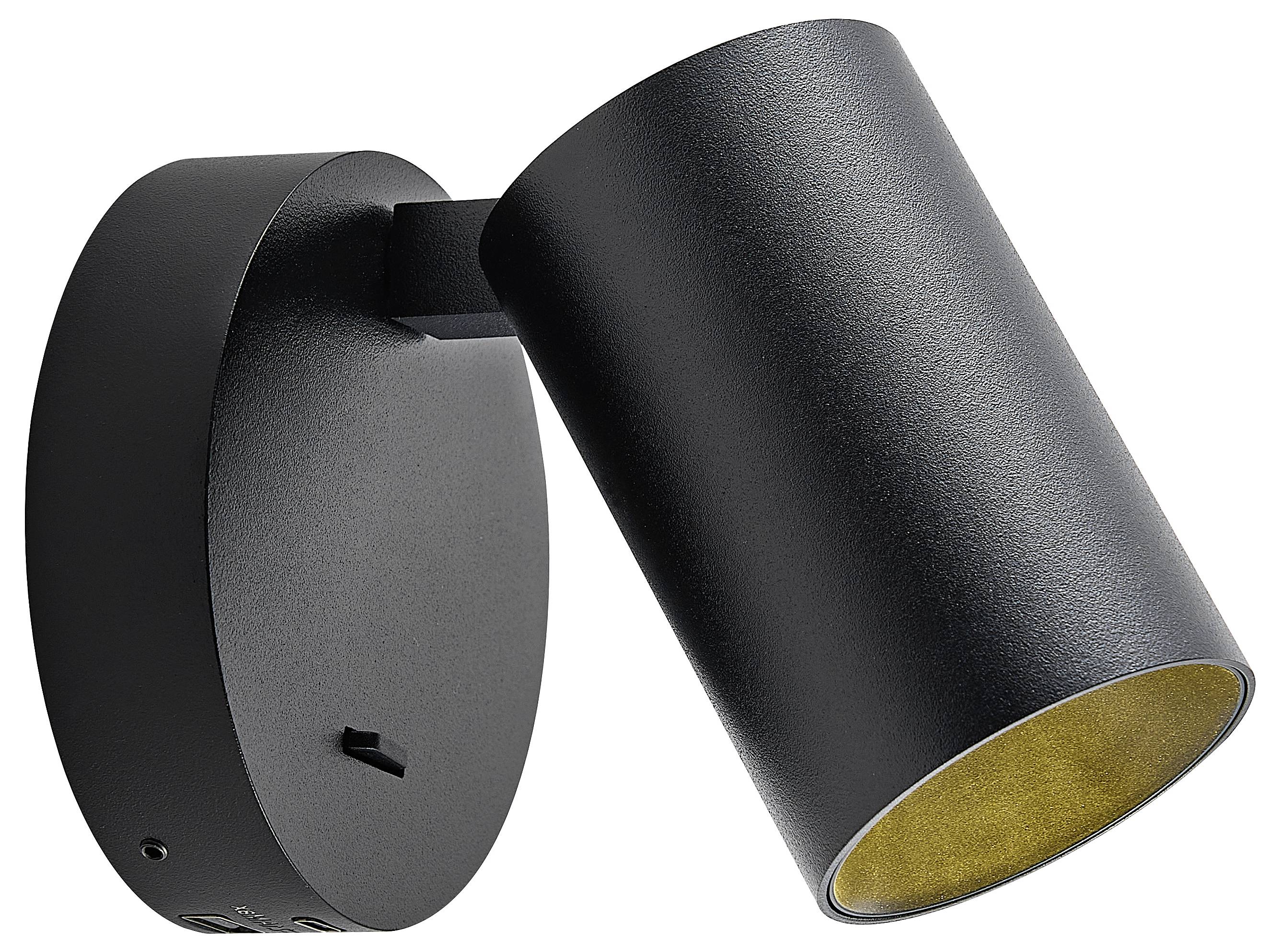 Czarna, cylindryczna lampa ścienna z regulowaną głowicą, zamontowana na ścianie, zapewnia kierunkowe oświetlenie do precyzyjnego doświetlania przestrzeni.