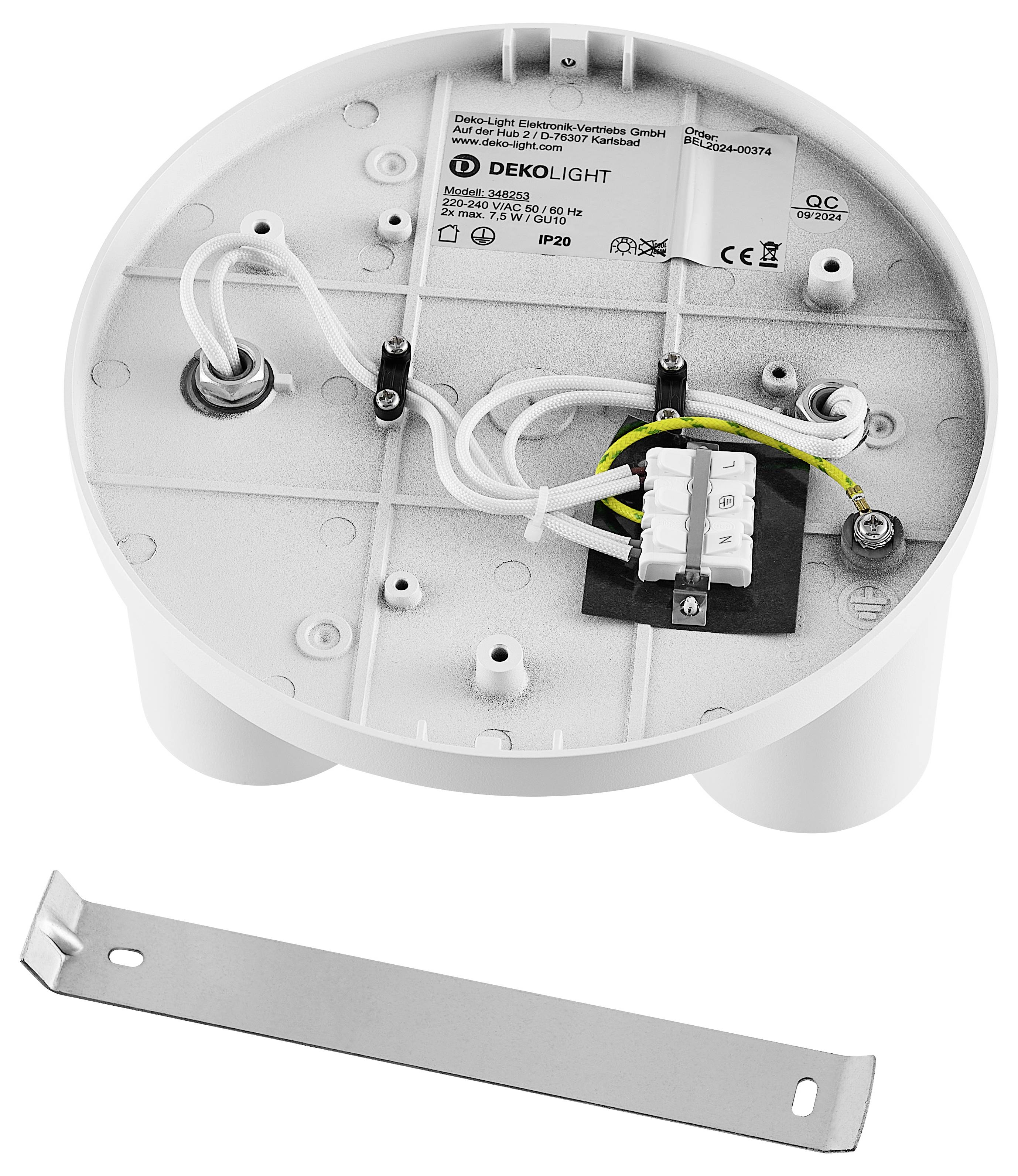 Okrągła płyta sufitowa w kolorze białym z przyłączami kablowymi, uziemieniem i otworami na śruby. Poniżej znajduje się srebrny uchwyt montażowy.