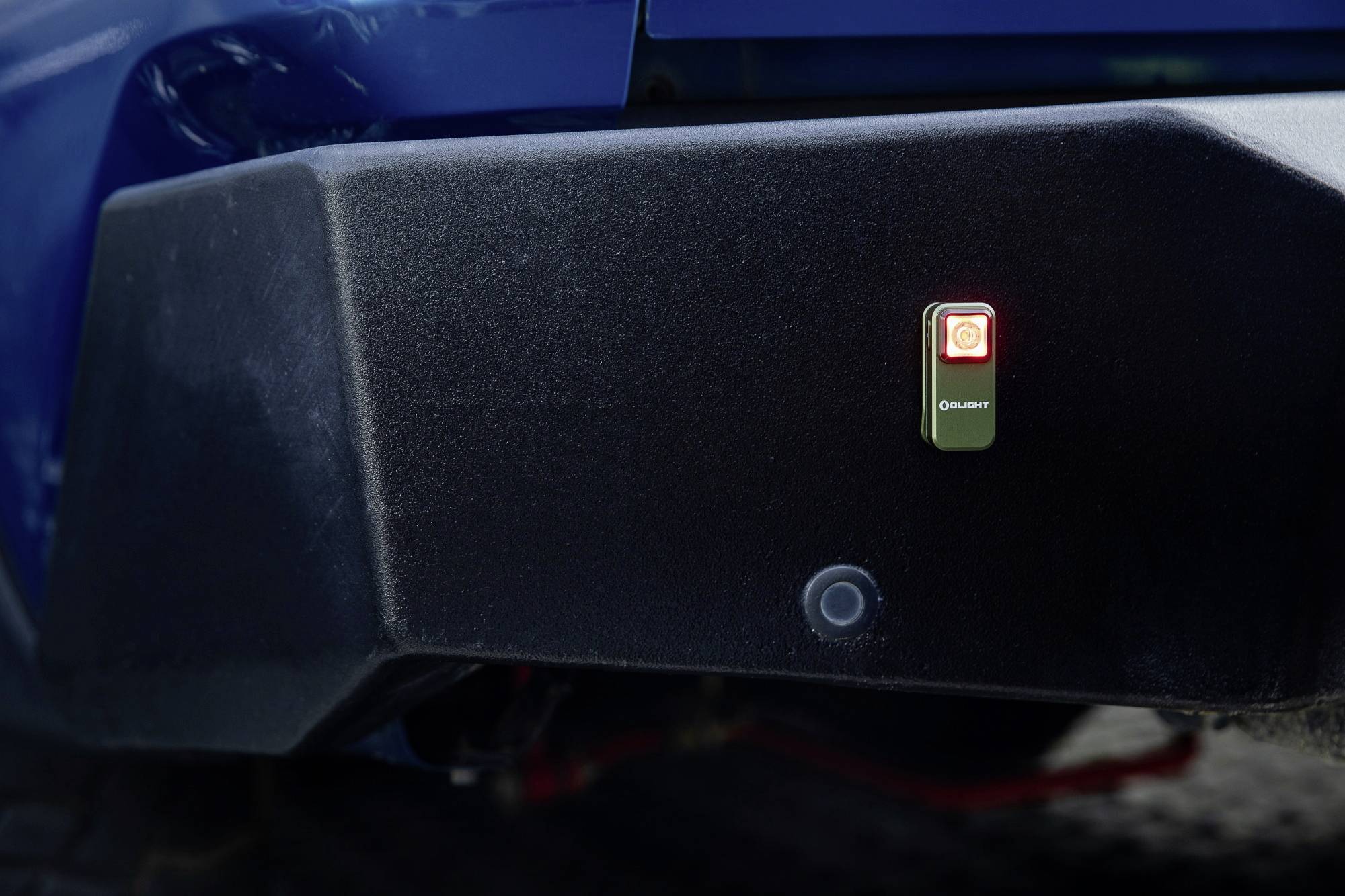 Duży czarny sprzęt z małym, świecącym czerwonym światełkiem pośrodku, zamocowany z tyłu niebieskiego pojazdu.