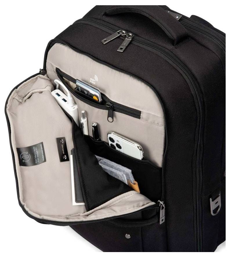 Czarny plecak z otwartą klapą, ukazujący kieszenie na smartfon, długopisy i inne małe przedmioty.