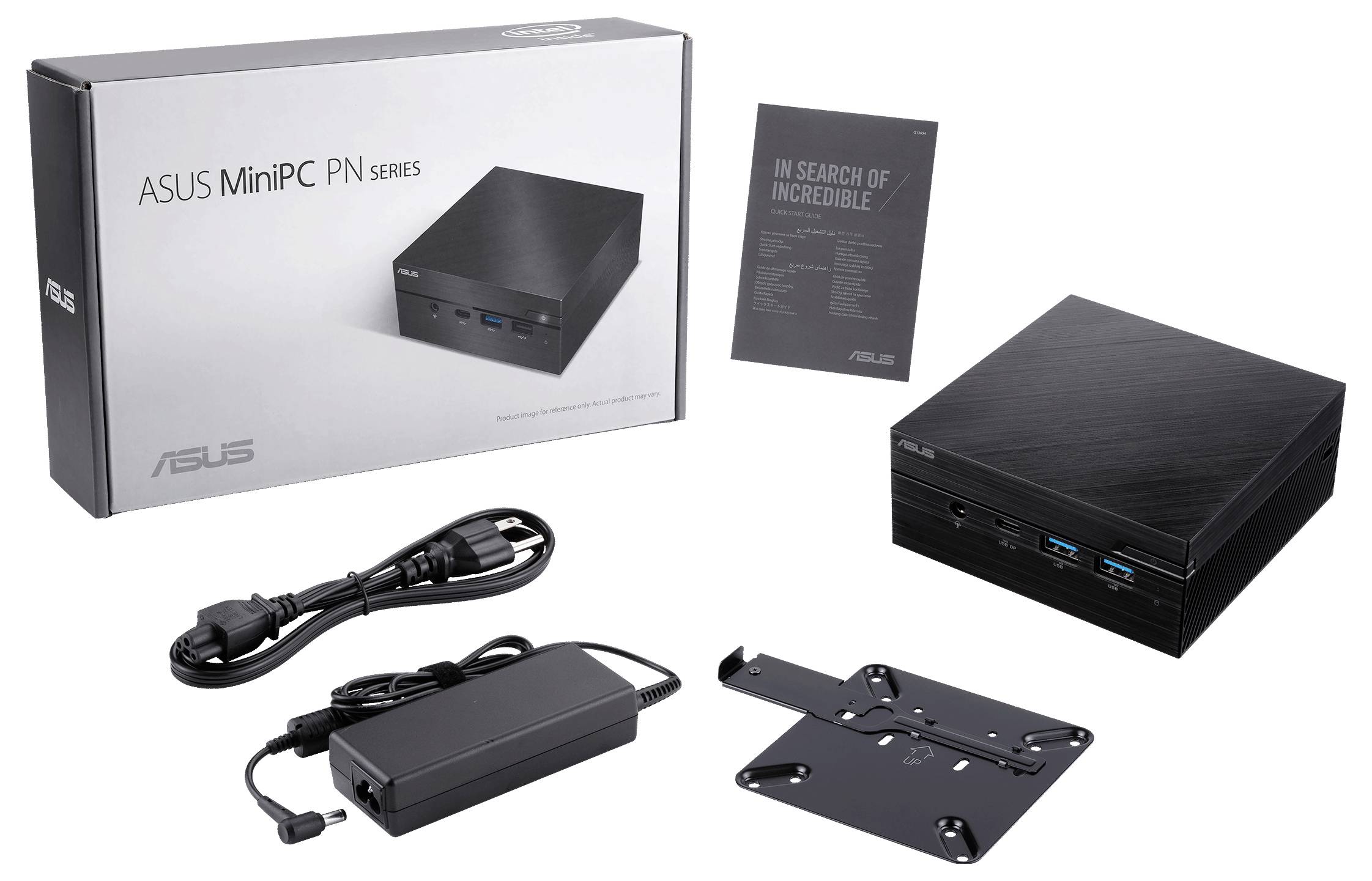 Miniaturowy komputer PC firmy ASUS z opakowaniem, zasilaczem, przewodami i uchwytem ściennym. Obok komputera leży prospekt z napisem 'W poszukiwaniu niezwykłości'.