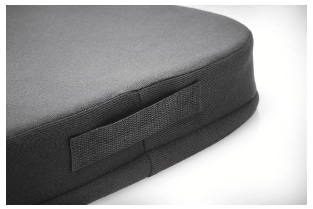 Poduszka siedzeniowa z zaokrąglonymi krawędziami i uchwytem do przenoszenia, wykonana z ciemnoszarego materiału. Idealna do zapewnienia komfortu i łatwego transportu.