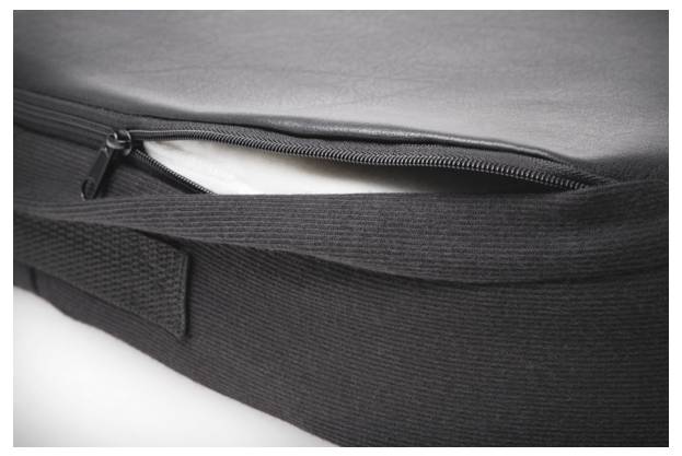 Rysunek przedstawia częściowo otwartą czarną torbę z zamkiem błyskawicznym, która ujawnia biały przedmiot wewnątrz.