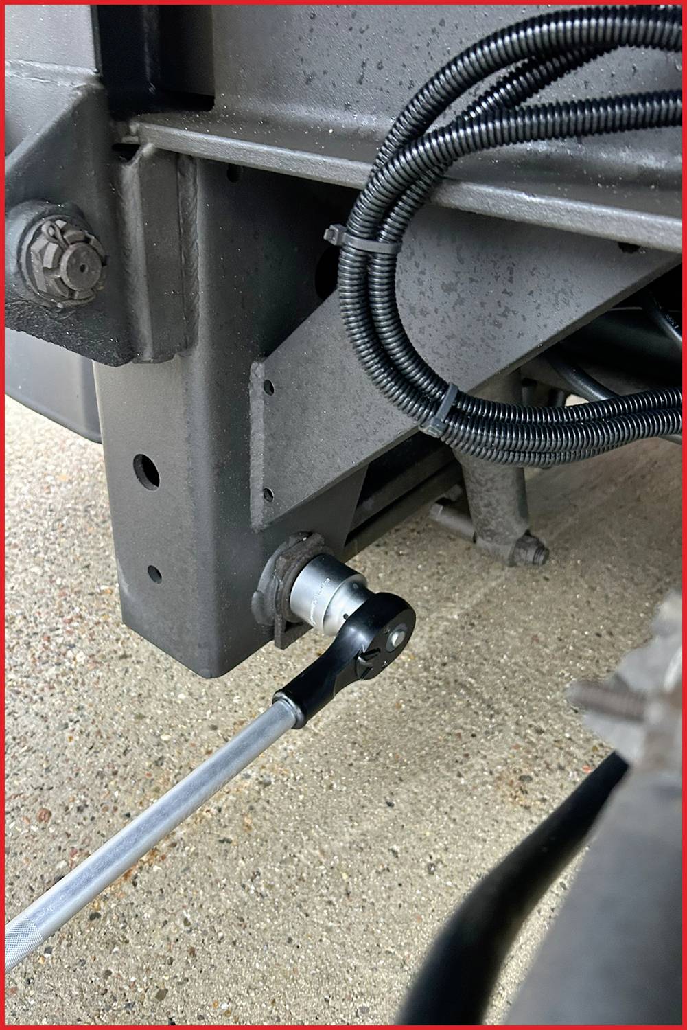 Zbliżenie mechanicznego połączenia w pojeździe. Metalowy pręt jest zamocowany z przegubem. Widoczne są przewody.