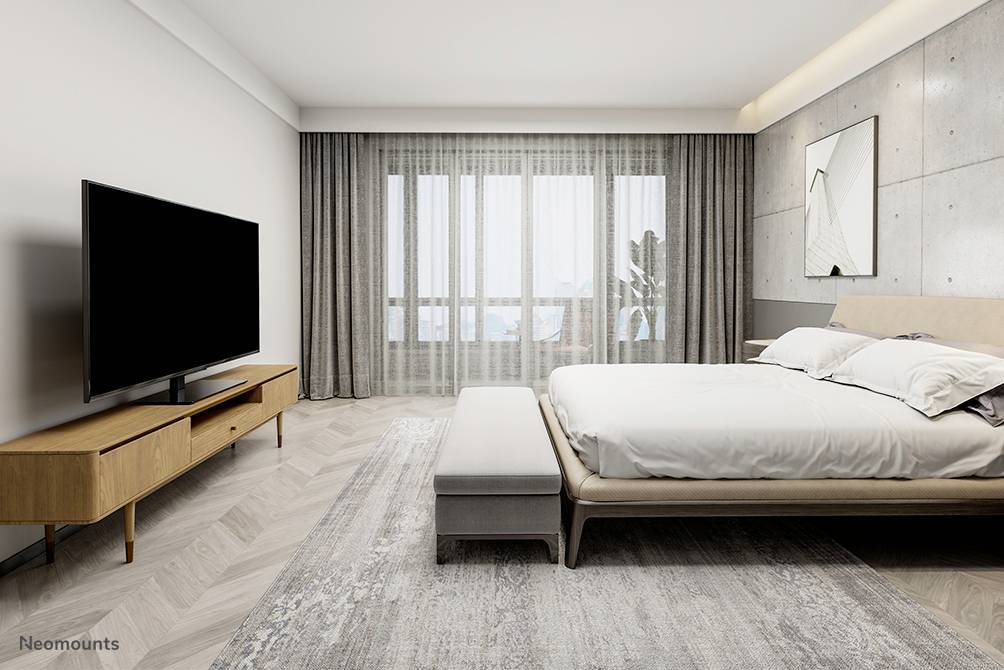 Sypialnia z nowoczesnym designem: duże łóżko, telewizor na drewnianej szafce, okno z szarymi zasłonami, jasne ściany i podłoga.