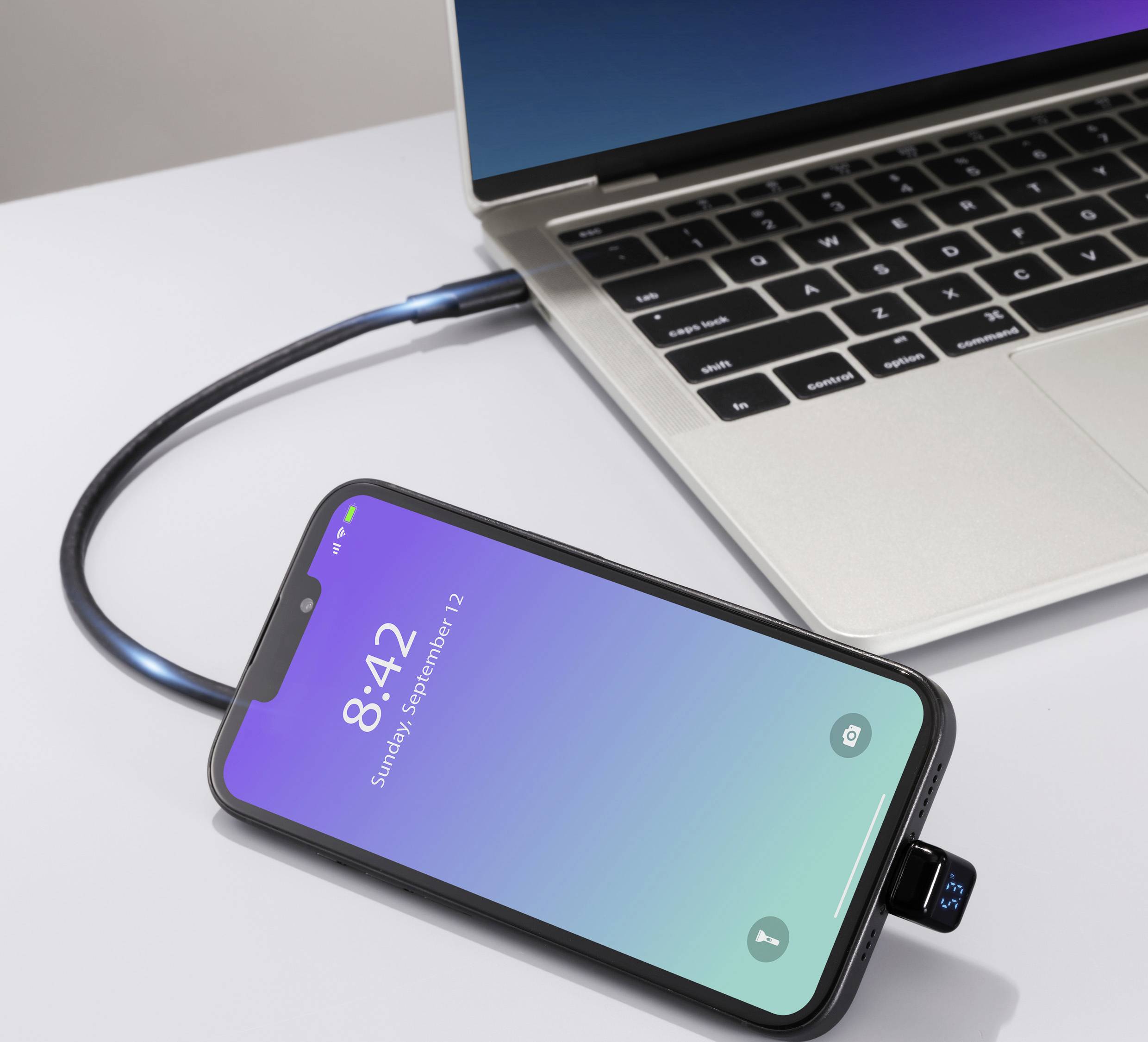 Smartfon podłączony kablem do laptopa, wyświetlający ekran blokady z godziną 8:42.