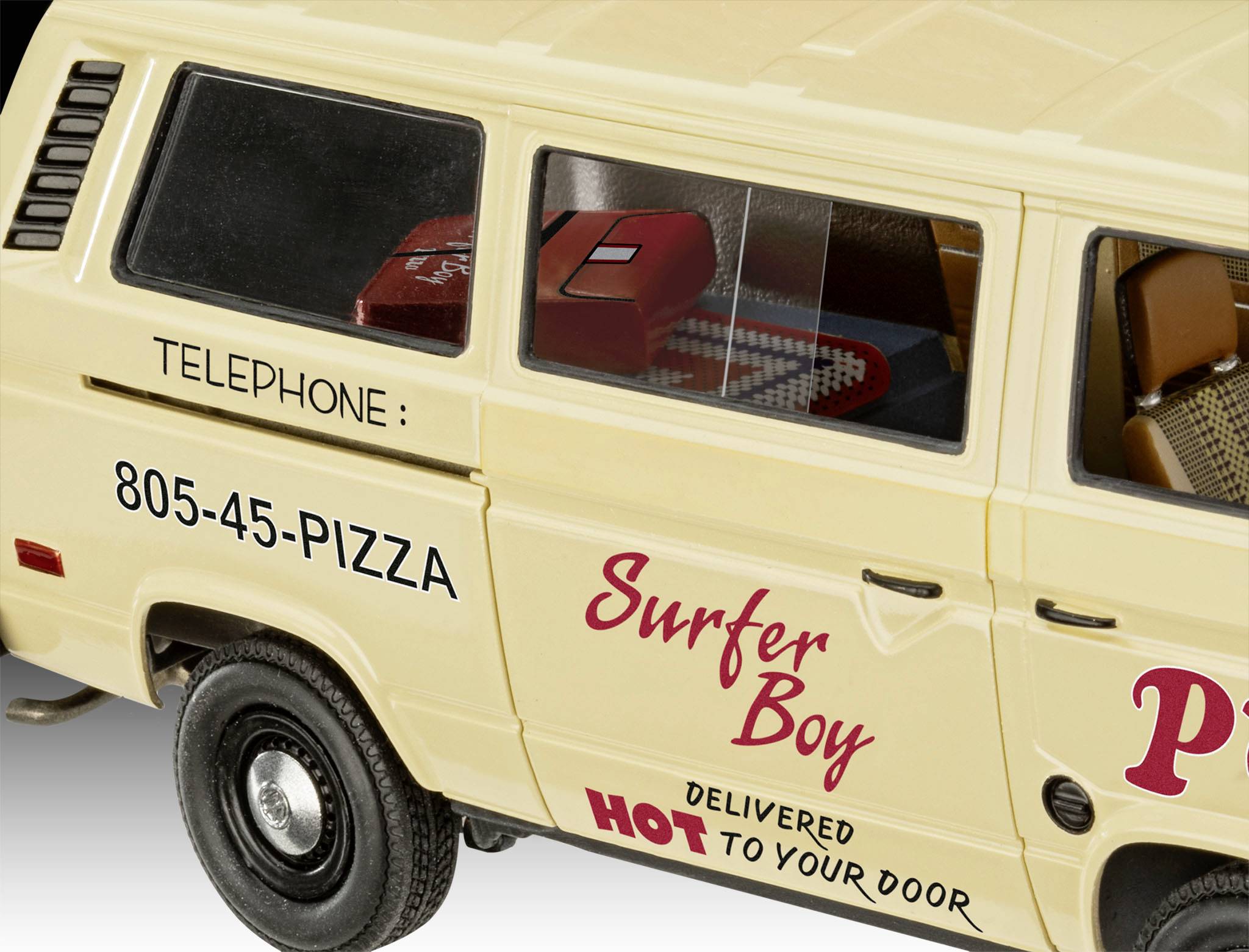 Żółty samochód dostawczy z napisem 'Surfer Boy Pizza' i '805-45-PIZZA'. Przez okno widać stół i siedzenia.