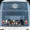Niebieski VW bus widziany od tyłu, z otwartą pokrywą silnika, która odsłania niektóre elementy mechaniczne. Logo Volkswagena jest wyraźnie widoczne.