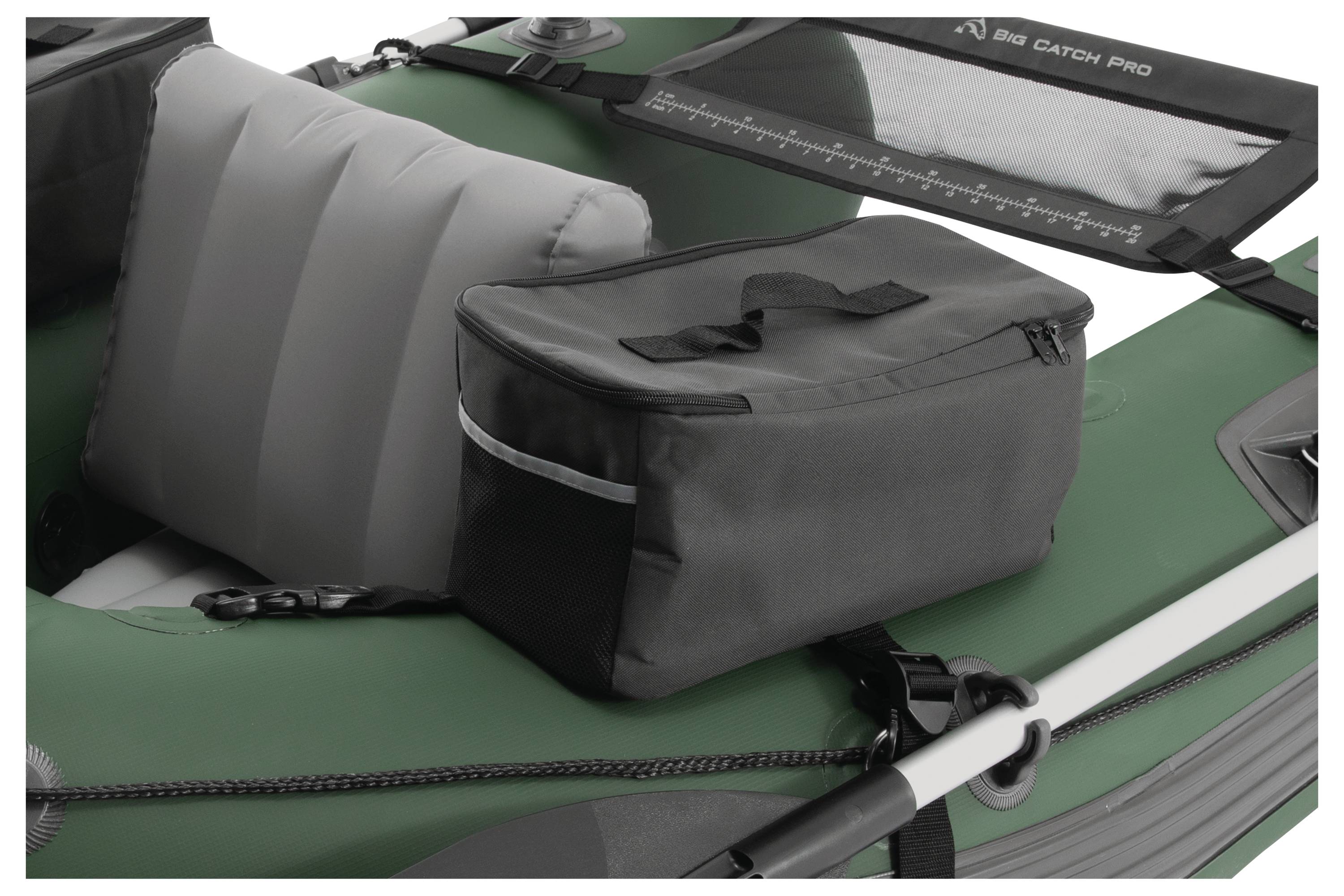 Dmuchana łódź z szarą poduszką siedzącą i czarną torbą transportową. Łódź posiada zielone boki z wiosłem zamocowanym na burcie.