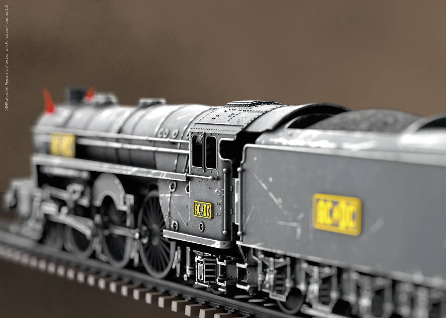 Metalowy model pociągu z dokładnymi szczegółami porusza się po torach. Pociąg jest czarny z żółtymi naklejkami z numerami.