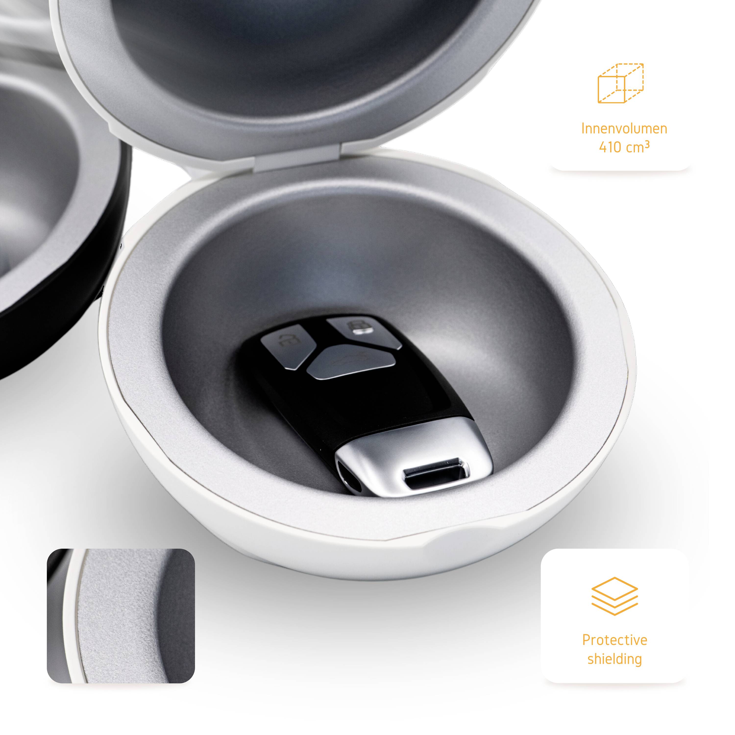 Otwarte okrągłe pudełko ochronne z kluczykiem samochodowym w środku. Na obrazku widoczny jest napis "Objętość wewnętrzna 410 cm³" oraz "Osłona ochronna".