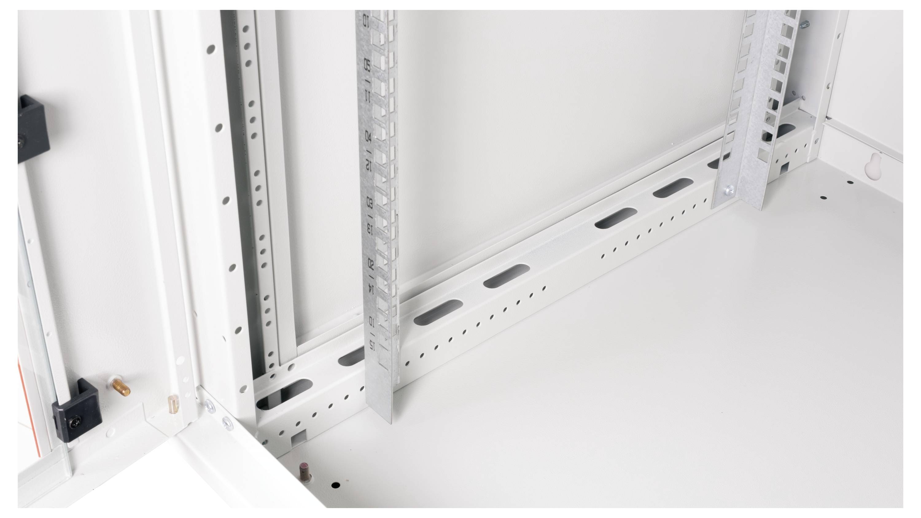 Wnętrze białej szafy serwerowej z metalowymi belkami podporowymi i perforowaną podstawą, prezentujące rozwiązania konstrukcyjne i funkcje zarządzania okablowaniem.