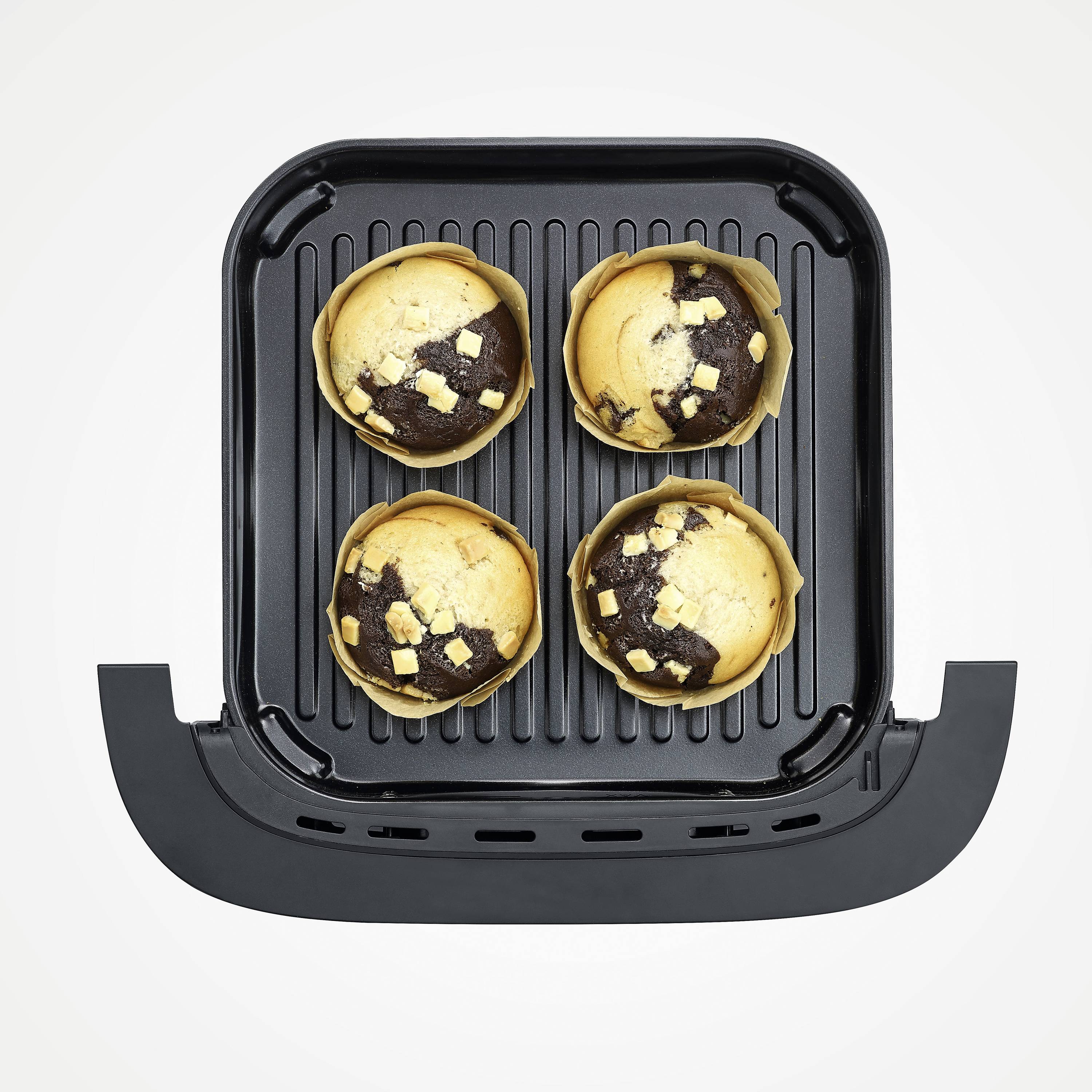 Cztery muffiny w wzorzystych papilotach na czarnej blasze do pieczenia.