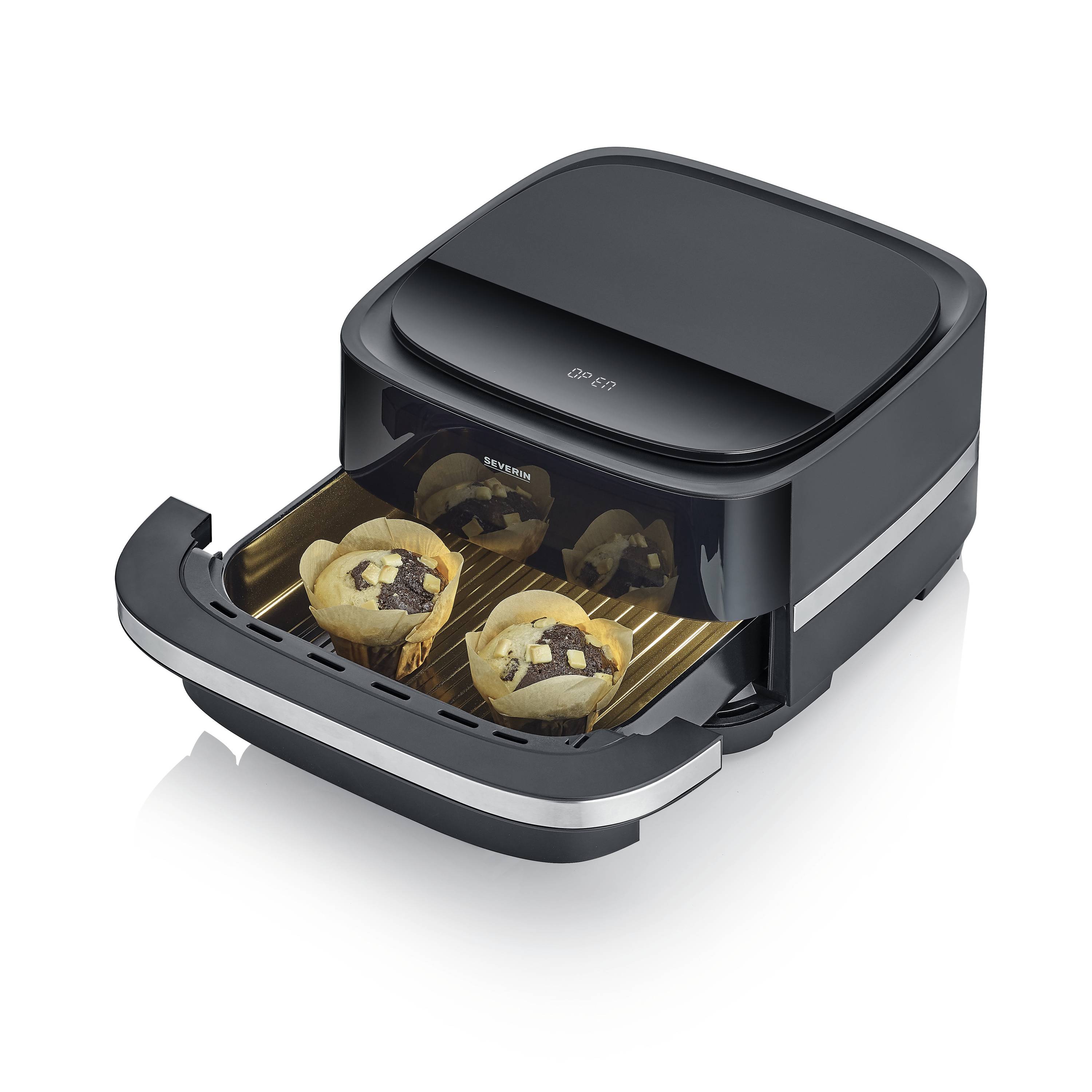 Czarny mini piekarnik z otwartą komorą, w której na kratce leżą trzy muffiny z kawałkami czekolady.