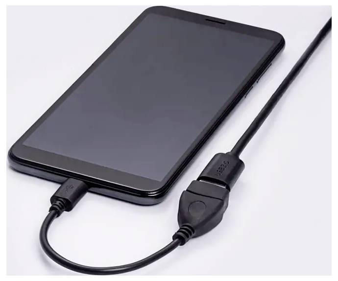 Smartfon leży na powierzchni, podłączony kablem USB do ładowania.