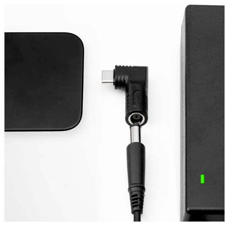 Czarna ładowarka z wtyczką USB-C jest podłączana do urządzenia. Zielone światło wskazuje gotowość do pracy.