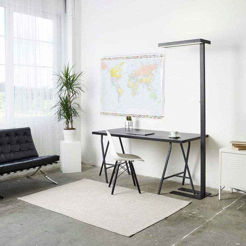 Minimalistyczne biuro z nowoczesnym biurkiem, krzesłem, lampą podłogową, rośliną i mapą świata na ścianie. Okno wpuszcza światło dzienne.