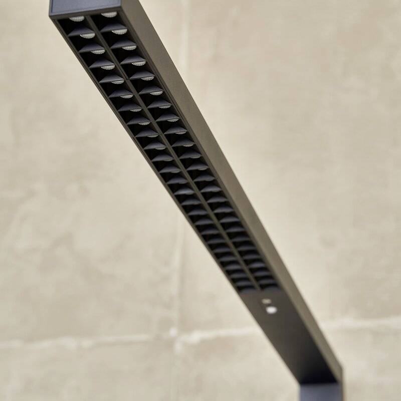 Ciemna, podłużna lampa z kwadratowymi otworami świetlnymi, umieszczona na beżowym tle.