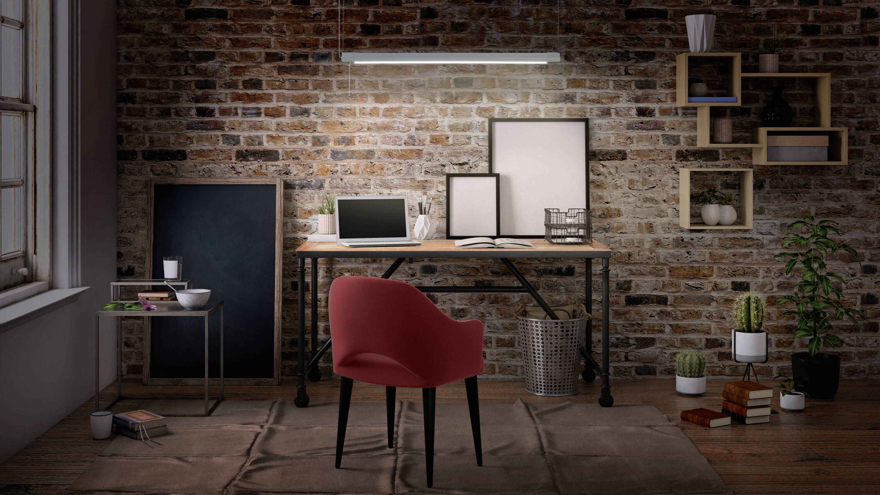 Czerwone krzesło przed biurkiem z laptopem, ramkami na zdjęcia i roślinami w nowoczesnym biurze z ceglaną ścianą i półkami.