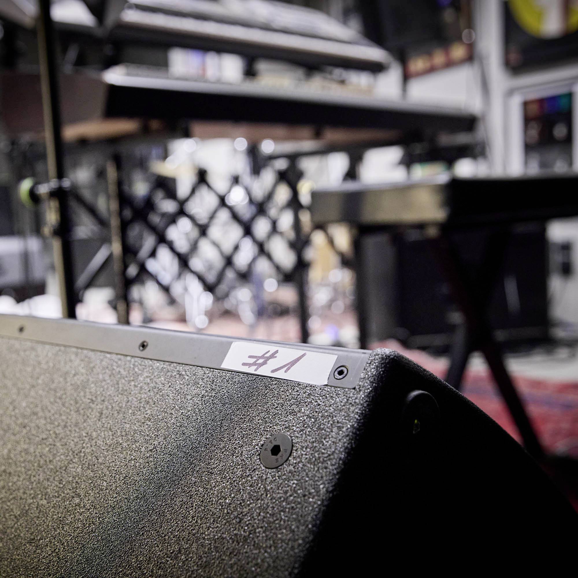 Widok na scenę z różnymi instrumentami muzycznymi w tle, na pierwszym planie wzmacniacz z napisem '#1'.