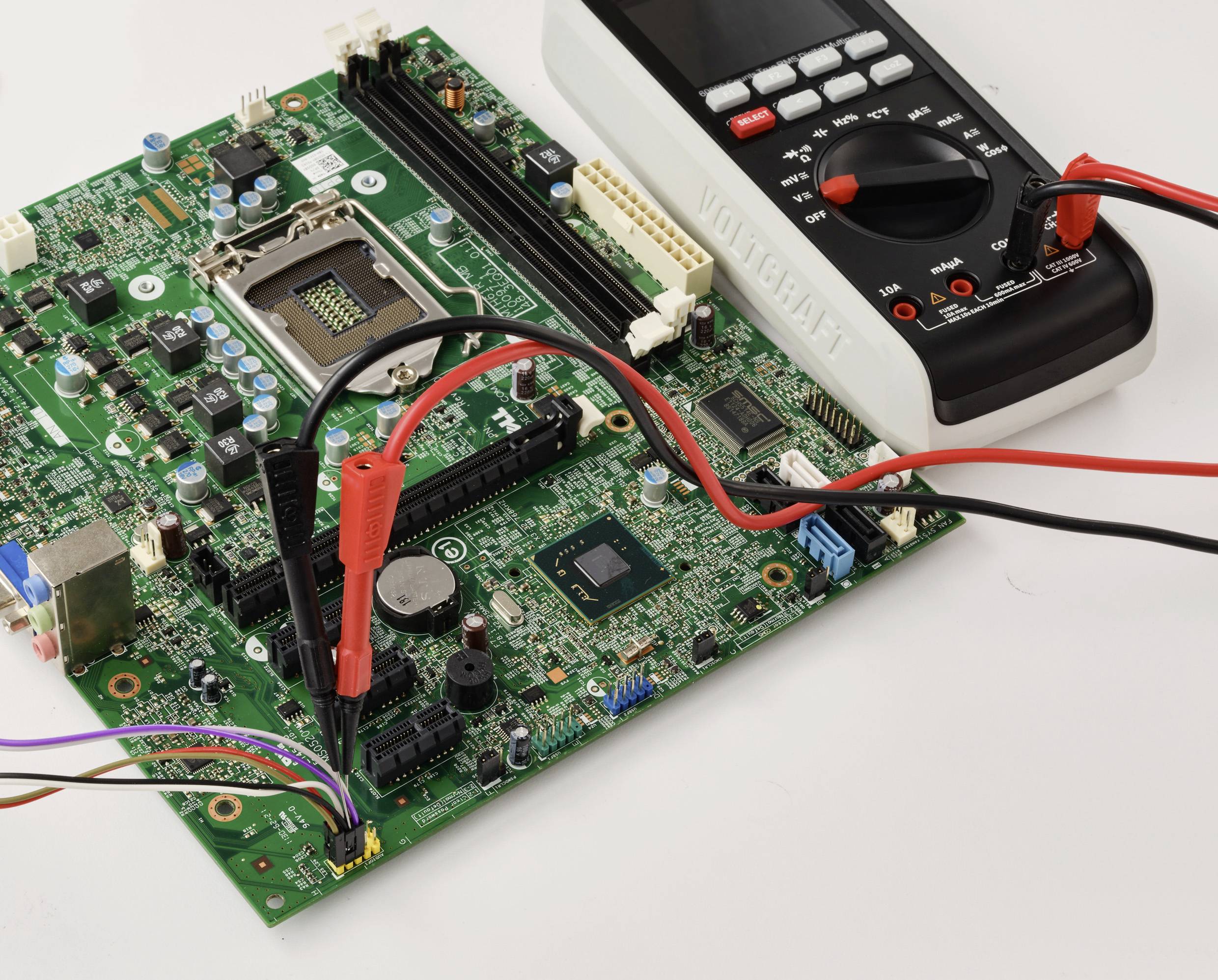 Cyfrowy multimetr z czerwonymi i czarnymi sondami jest podłączony do zielonej płytki drukowanej, mierzący napięcie lub natężenie prądu.