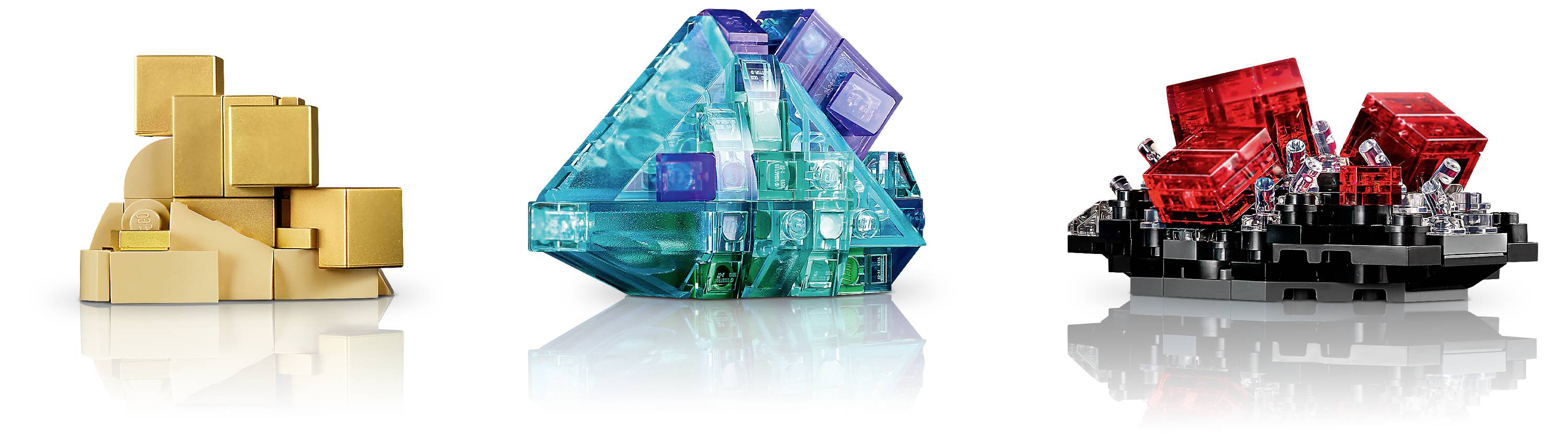 Trzy rzeźby abstrakcyjne: po lewej złoty stos sześcianów, w centrum niebiesko-różowe formy trójkątne, po prawej czerwone sześciany na czarnej podstawie. Połyskujące powierzchnie.