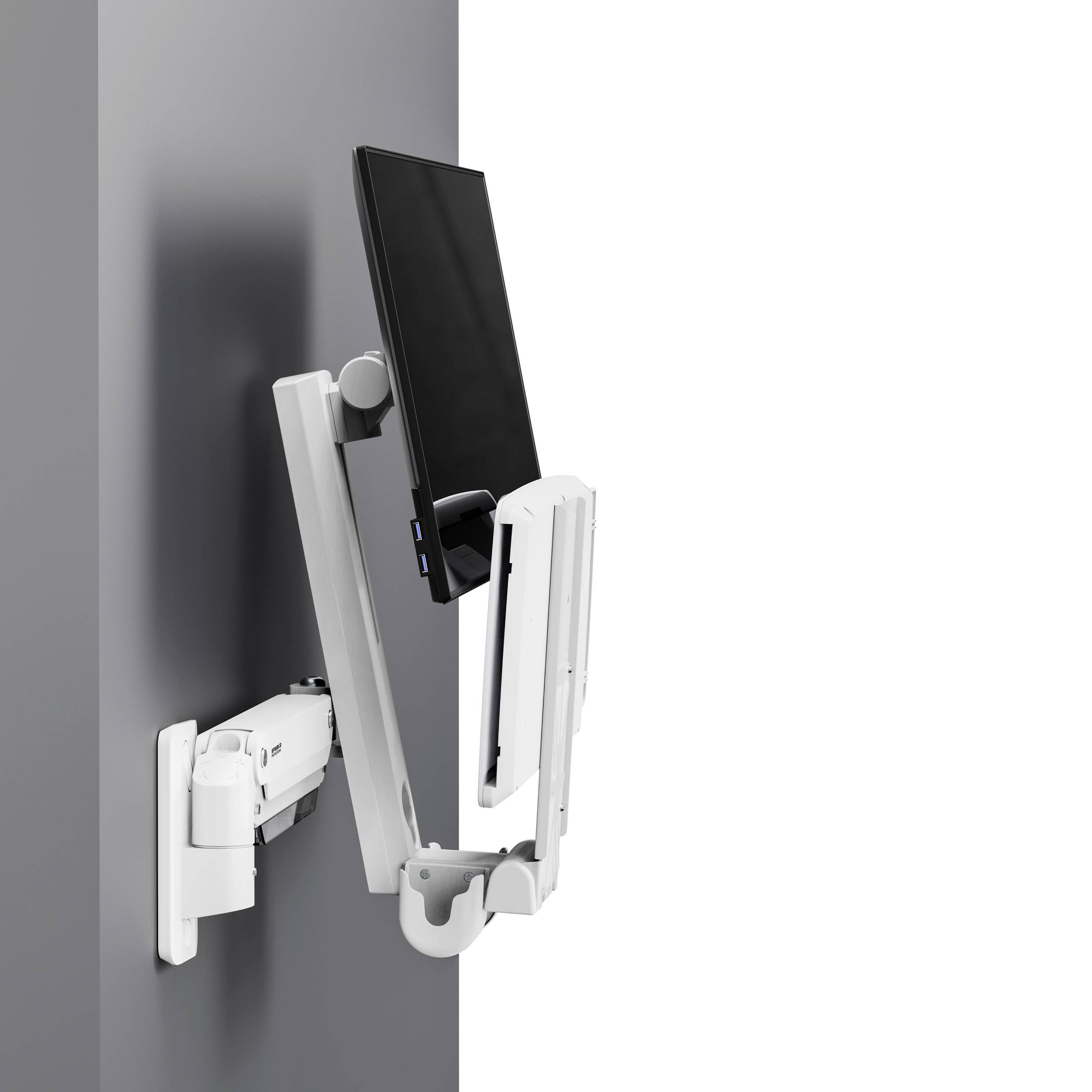 Tablet zamontowany na eleganckiej, regulowanej białej ściennej podstawce, umożliwiającej wszechstronne ustawienie obok pionowej szarej powierzchni.