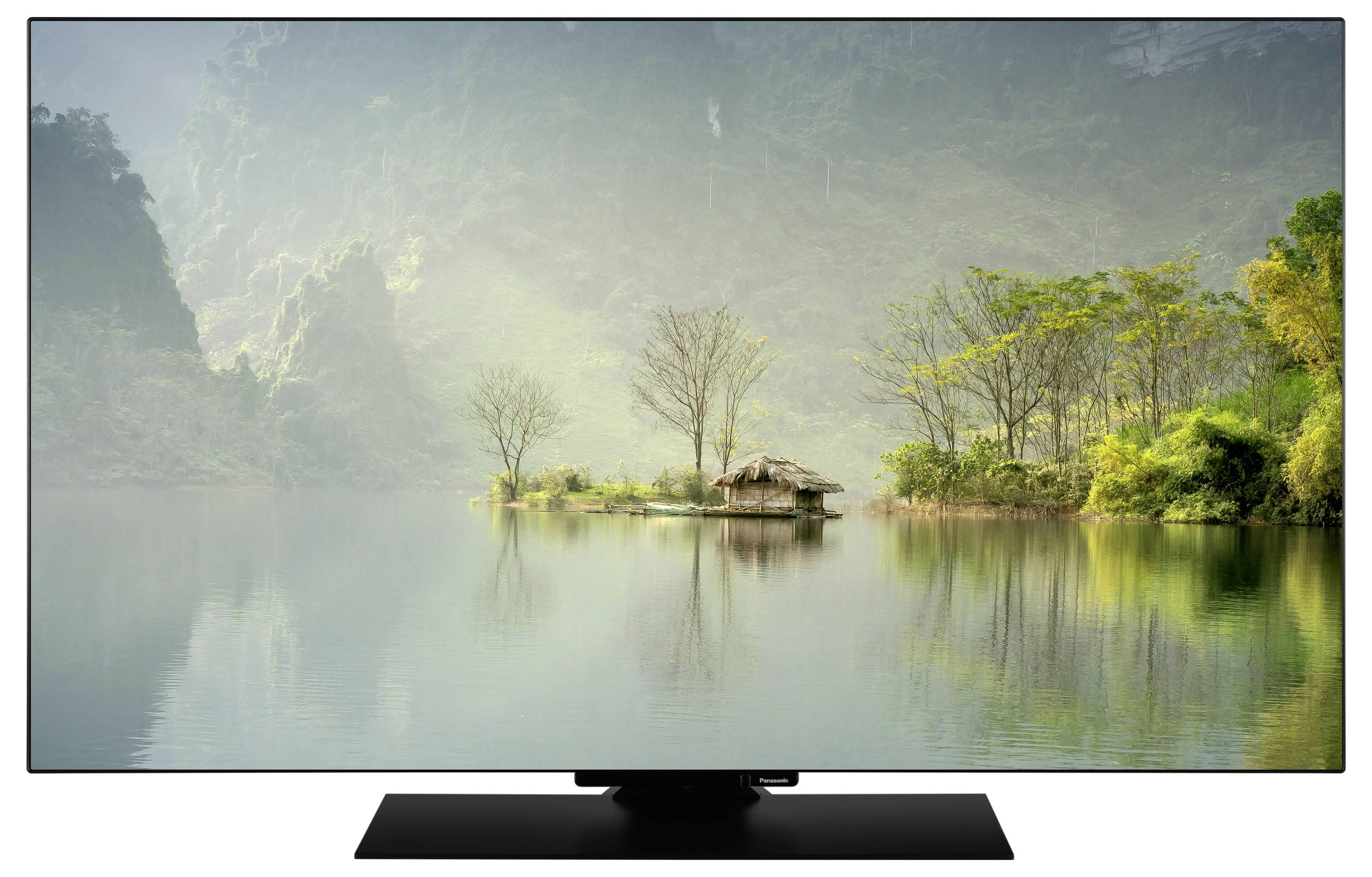 Chata na małej wyspie otoczonej spokojną wodą i bujną zielenią, z mglistymi wzgórzami w tle.